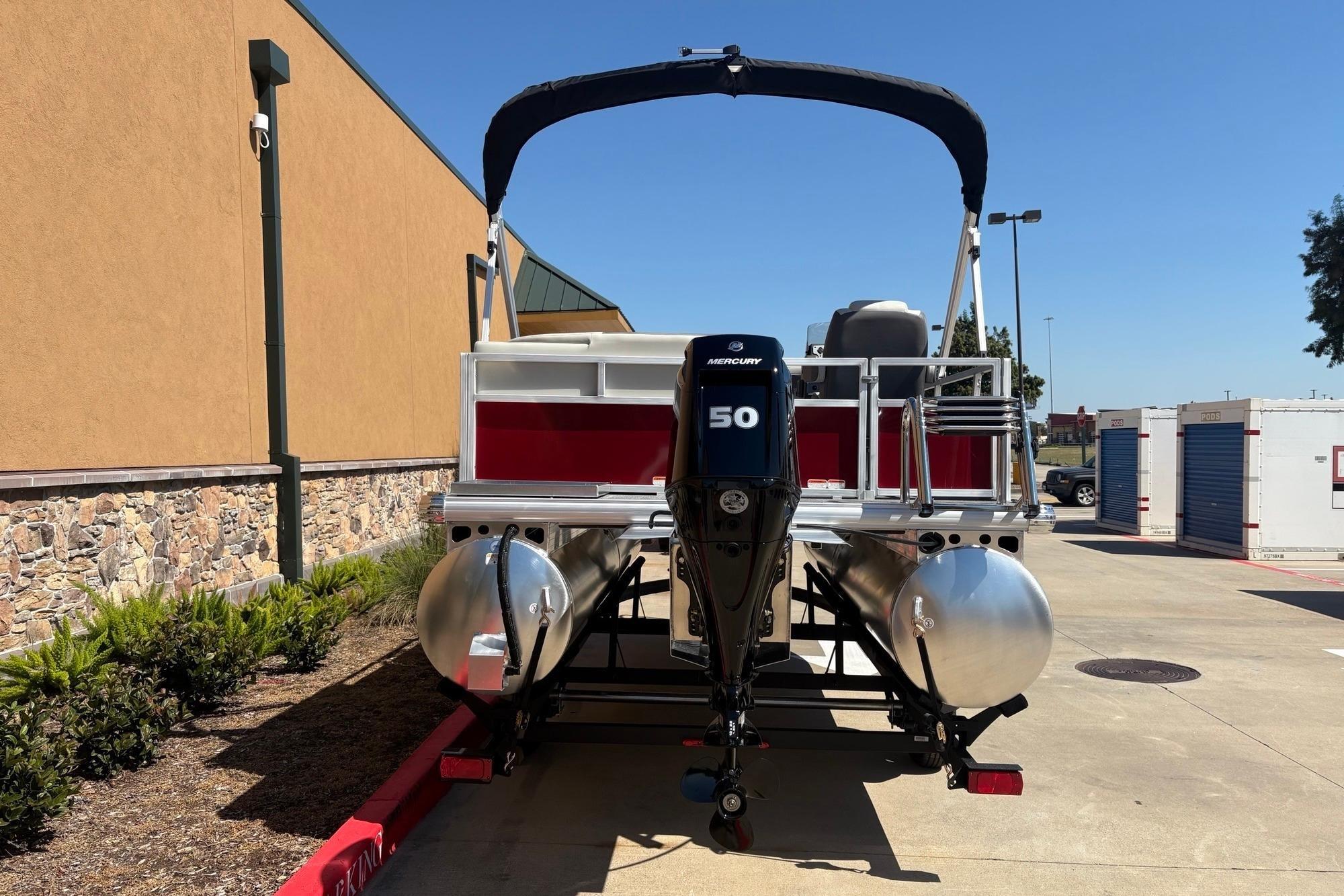 2026 Sun Tracker Bass Buggy 16 XL Select pontoon boat with Mercury 50 engine, parked outdoors.