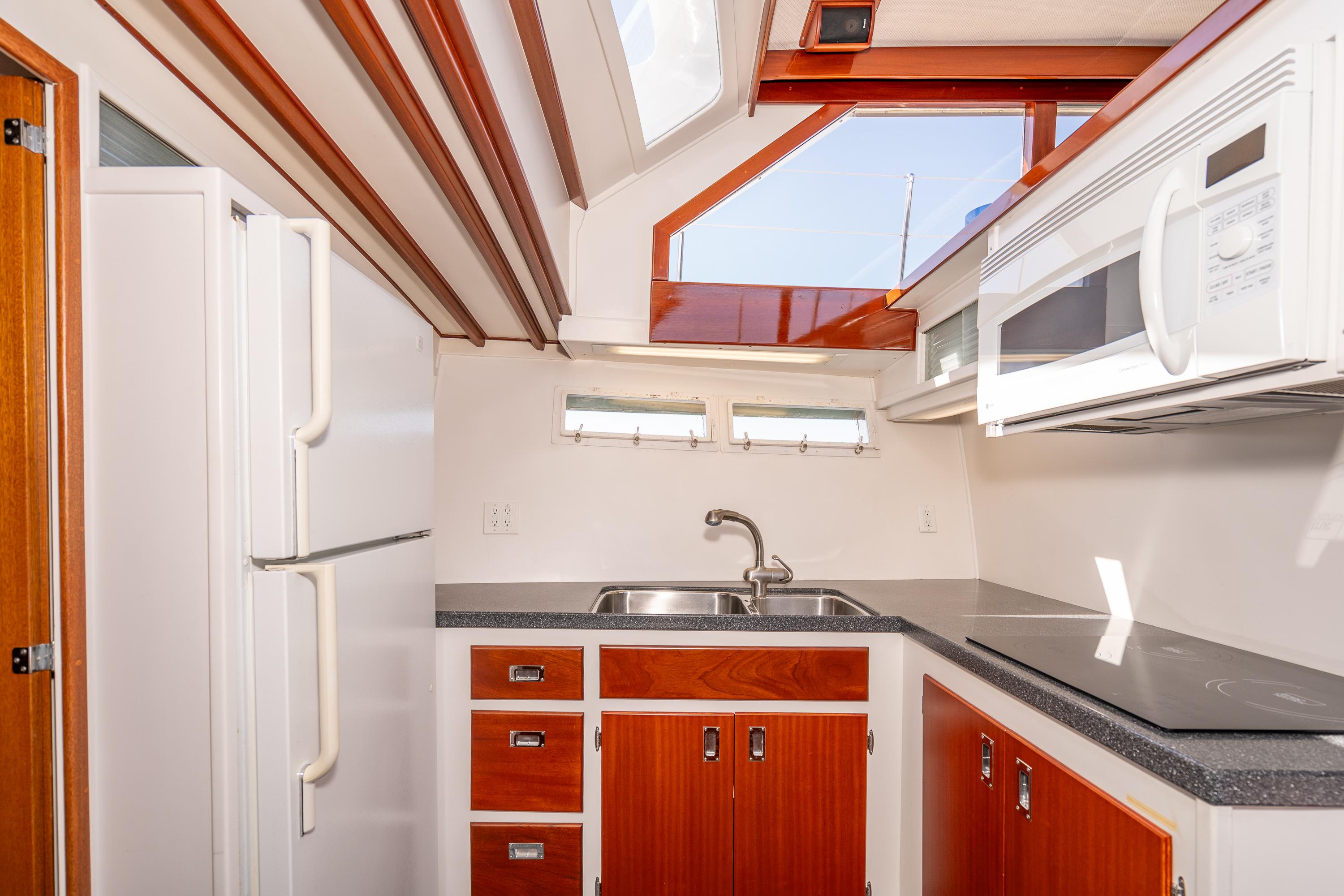 1965 Chris-Craft 57 Constellation kitchen with wood cabinets, sink, and modern appliances.