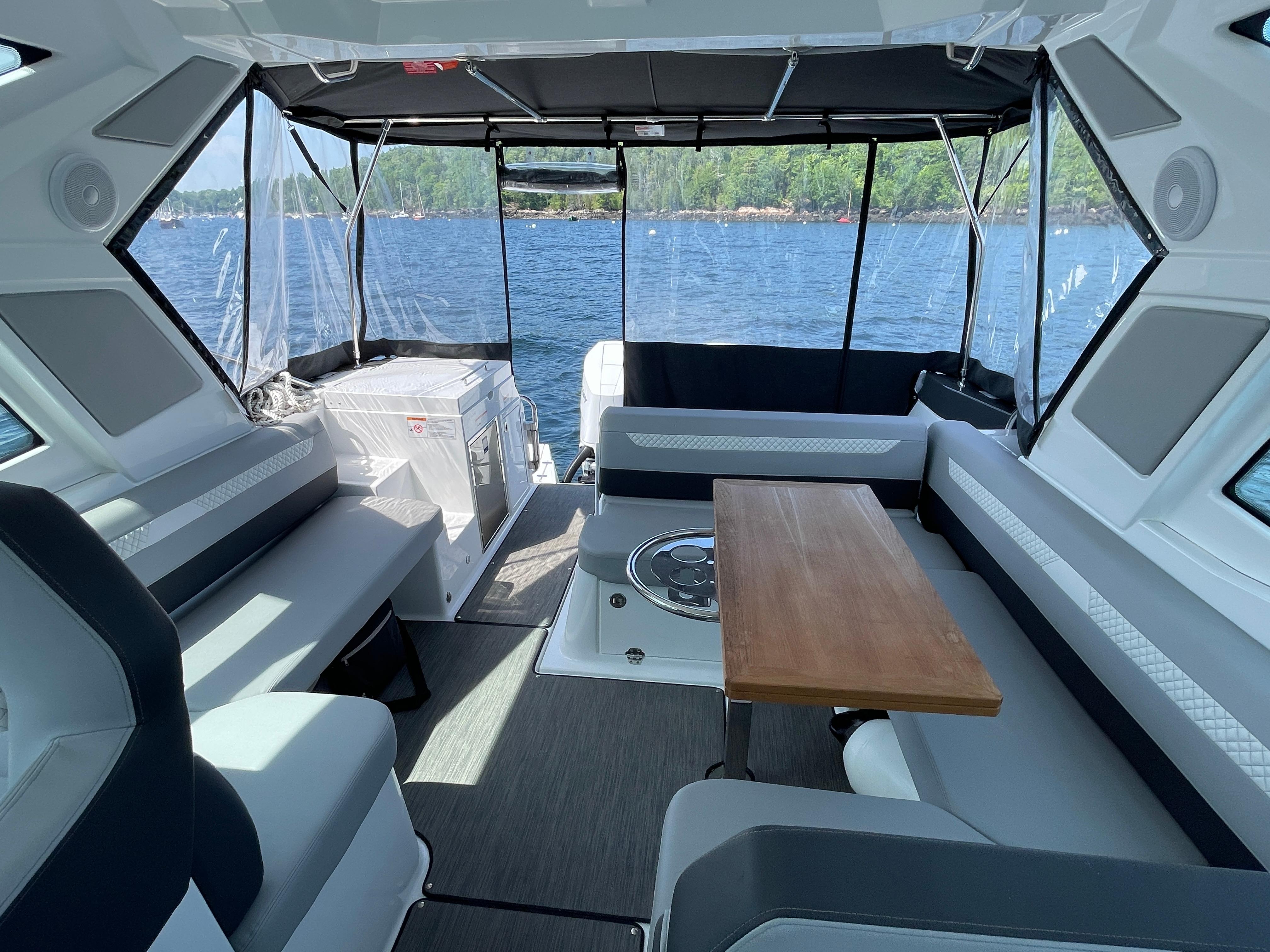Interior of 2024 Beneteau Gran Turismo 36 yacht with seating and table, overlooking water.
