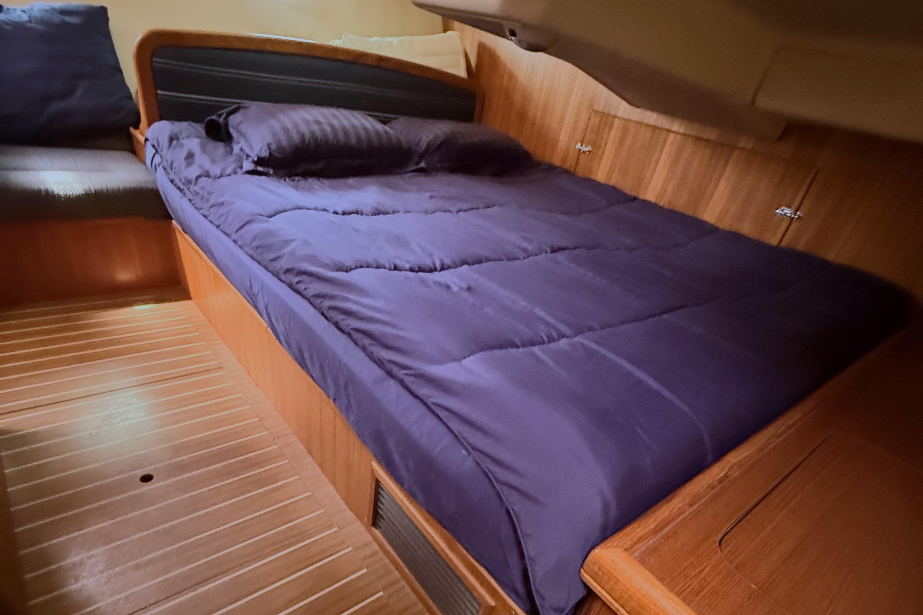 Cozy cabin interior of 2007 Hunter 38 sailboat with wooden flooring and a comfortable bed.