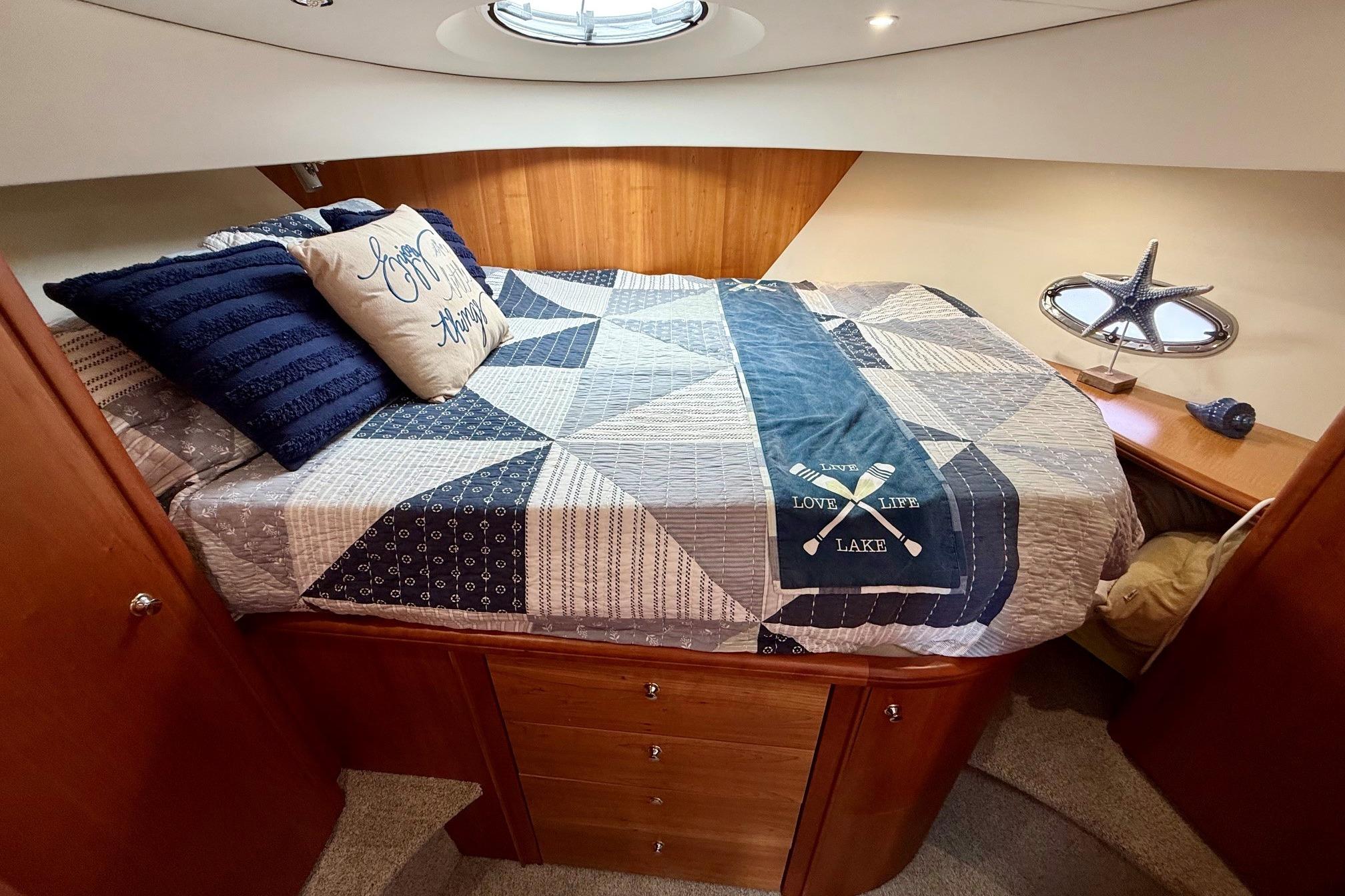Cozy bedroom in 2004 Silverton 39 Motor Yacht with nautical decor and quilted bedding.