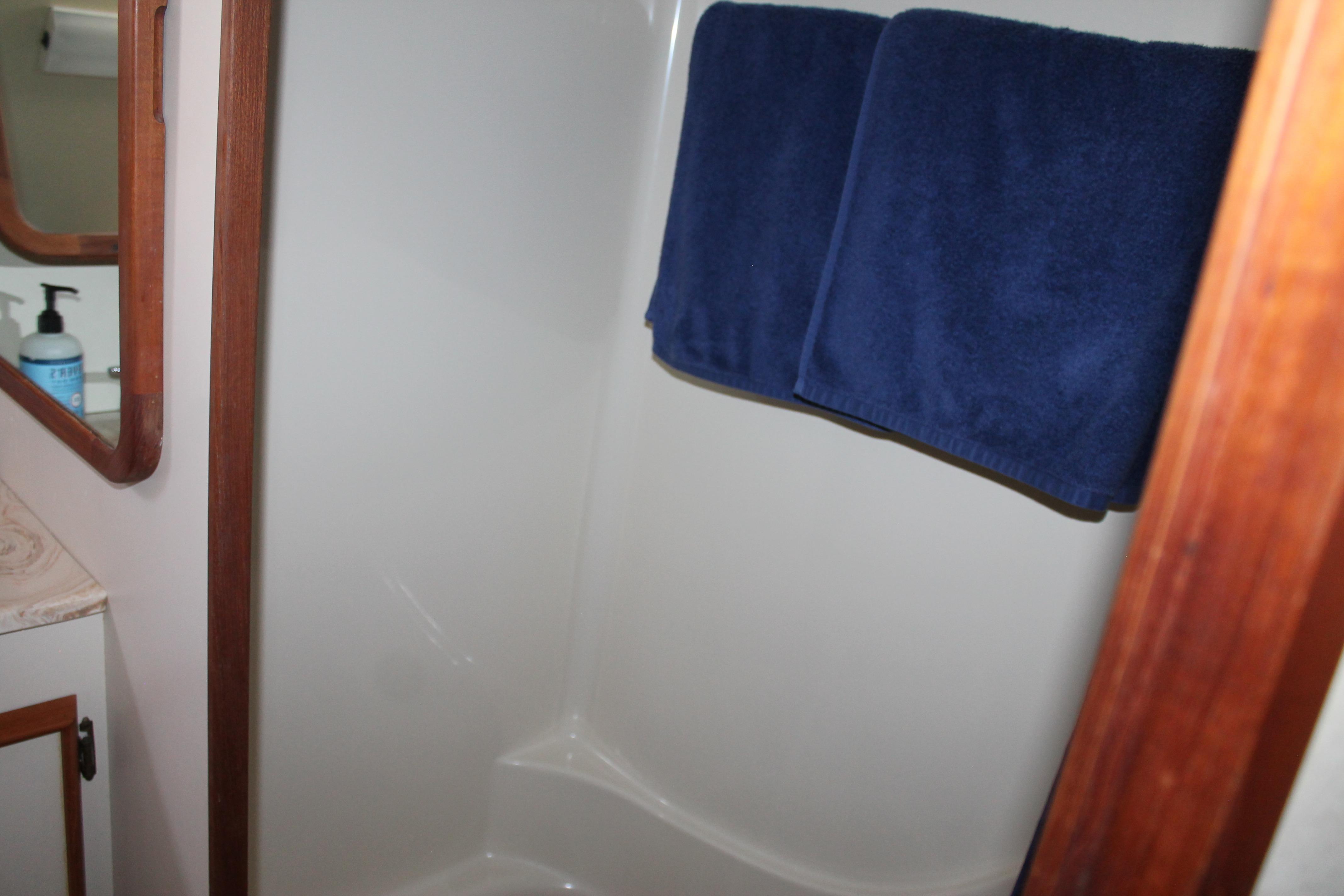 Shower area in 1987 Chris-Craft 427 Catalina with blue towels and wooden accents.