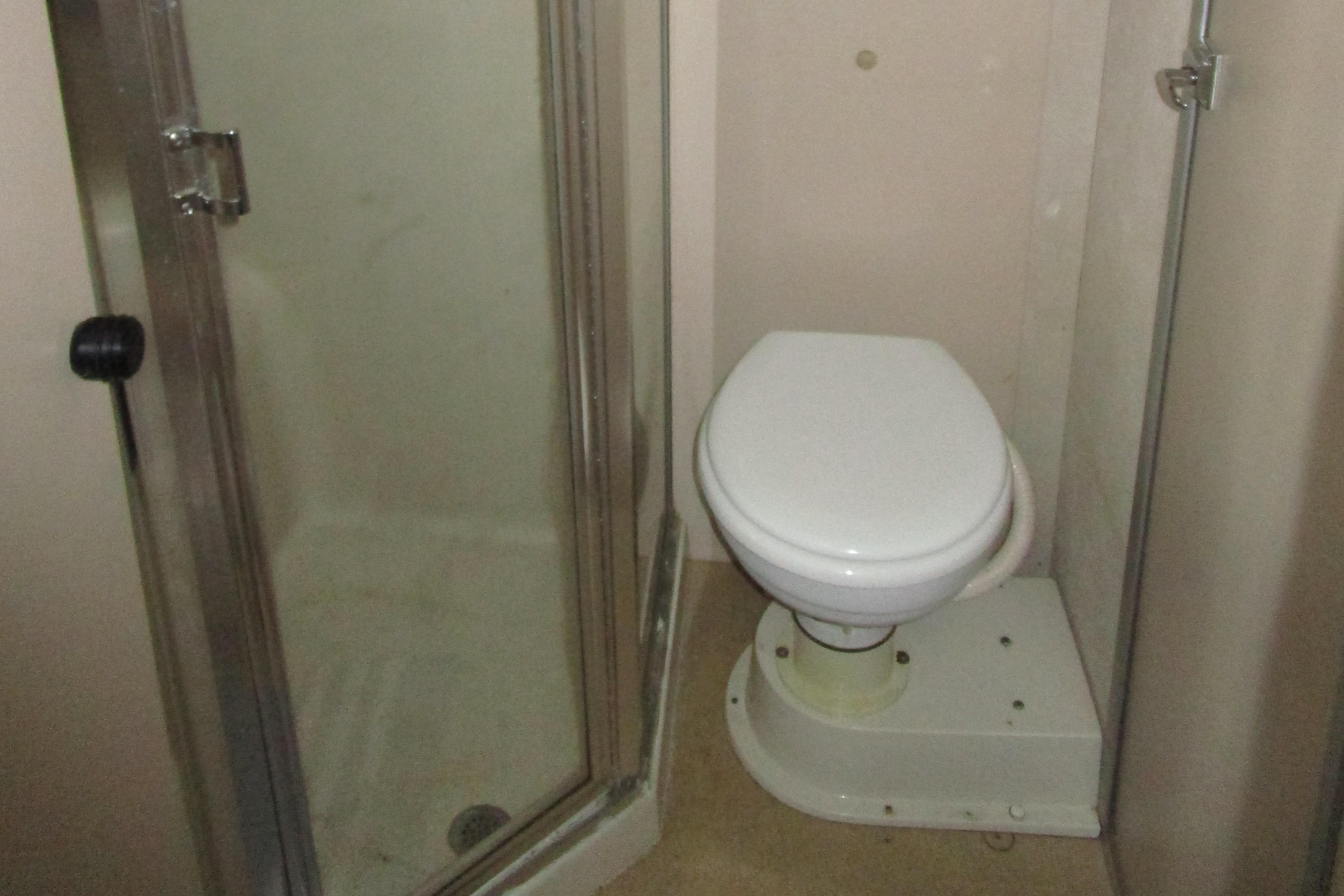 Bathroom with shower and toilet in 1990 Silverton 37 Convertible boat.