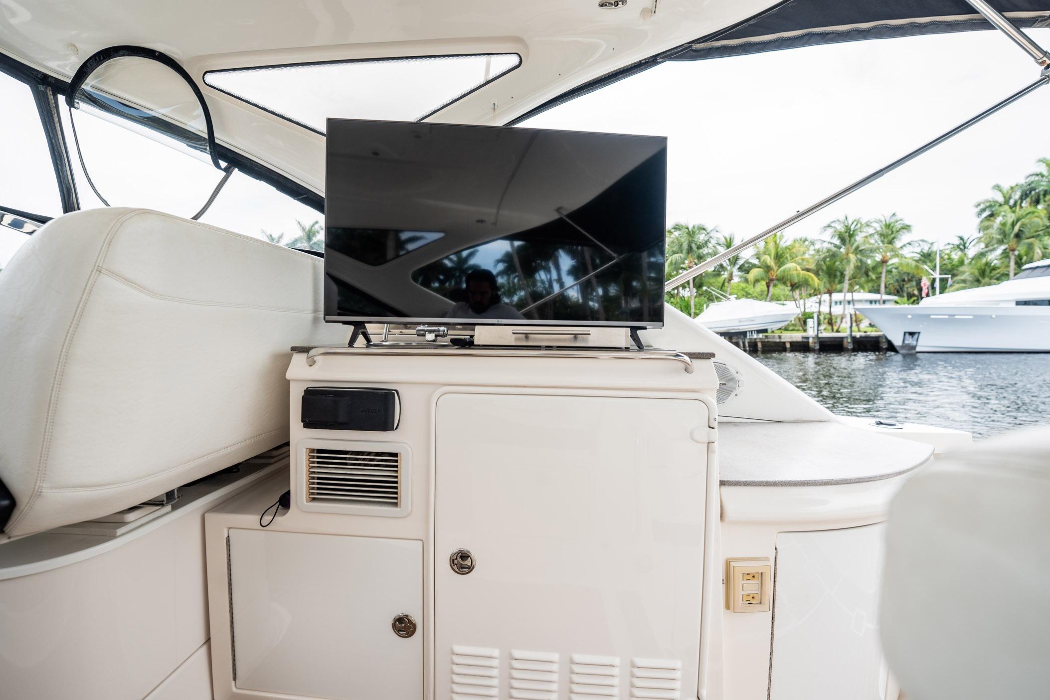 Luxury yacht interior with TV, Regal Commodore 4460, 2008 model, docked near palm trees.