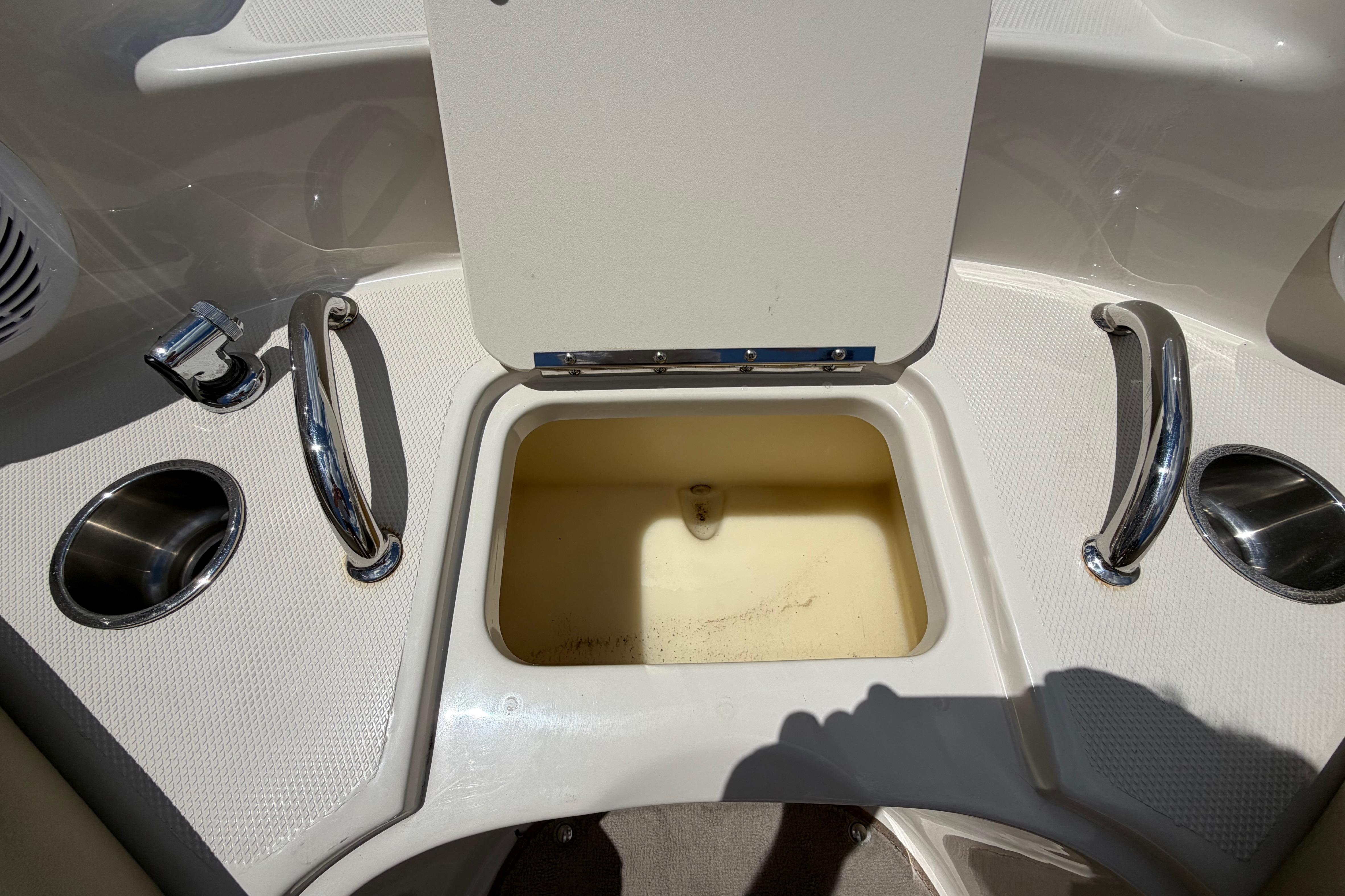 Open storage compartment on a 2004 Sea Ray 240 Sundeck boat deck.