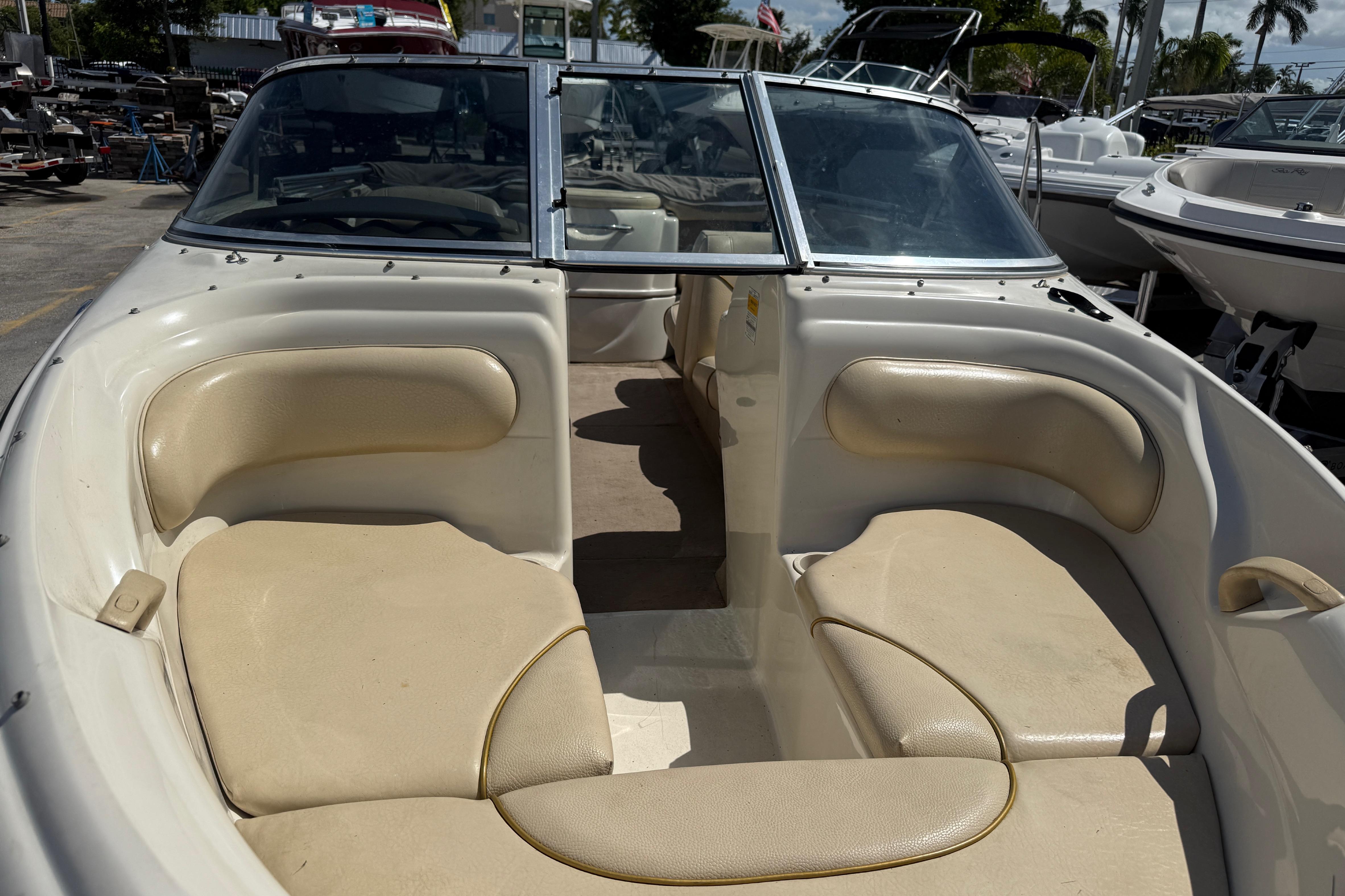 2001 Sea Ray 180 Bow Rider interior with beige seating, docked among other boats.