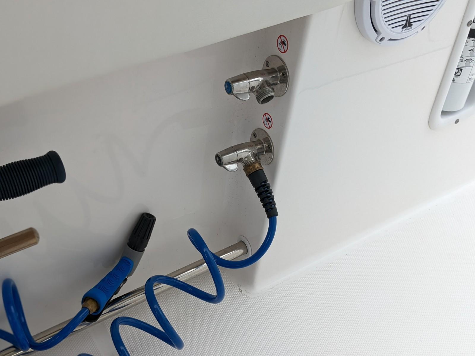 2021 Edgewater 262 CC boat fittings with blue coiled hose and stainless steel connectors.