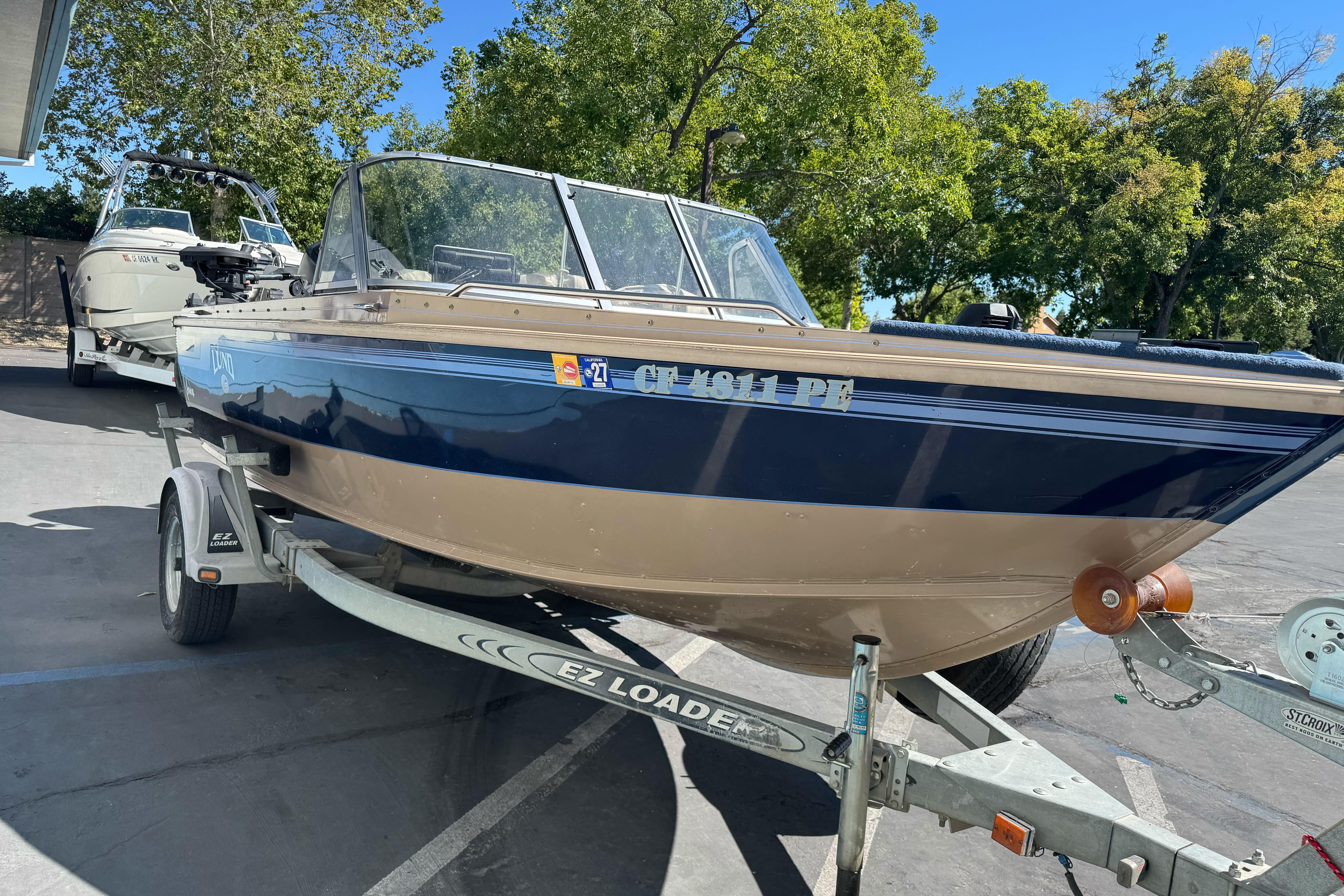 1998 Lund 1700 Pro Sport boat on EZ Loader trailer, parked outdoors.