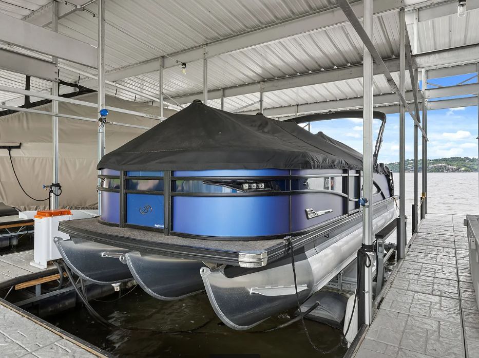 A 2023 Barletta CORSA 23QC pontoon boat is docked under a covered area.