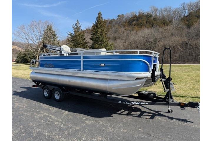 2026 Sun Tracker Fishin' Barge 20 DLX pontoon boat on trailer, parked outdoors.