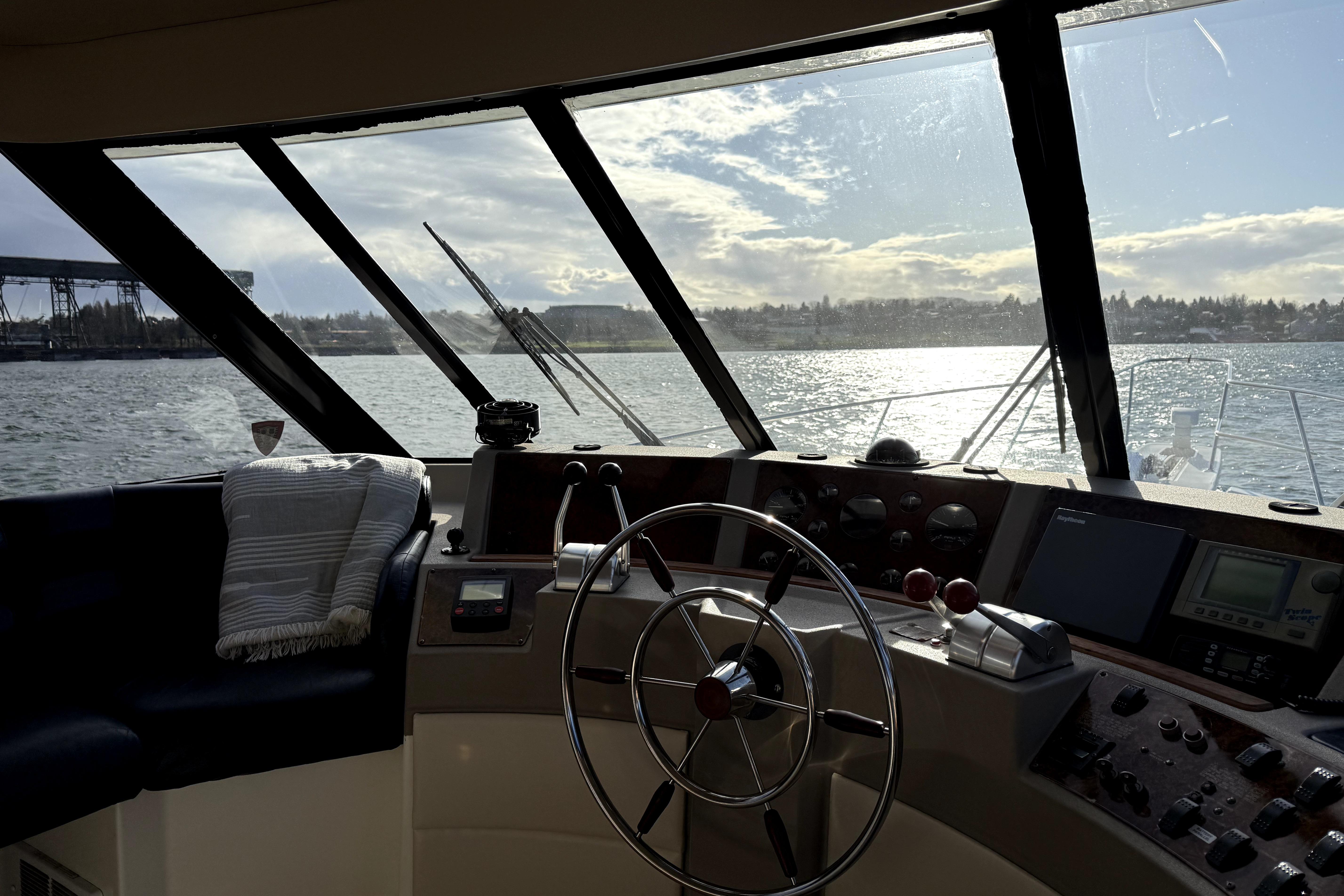 Interior view of 1998 Bayliner 4788 Pilot House Motoryacht helm with scenic water view.