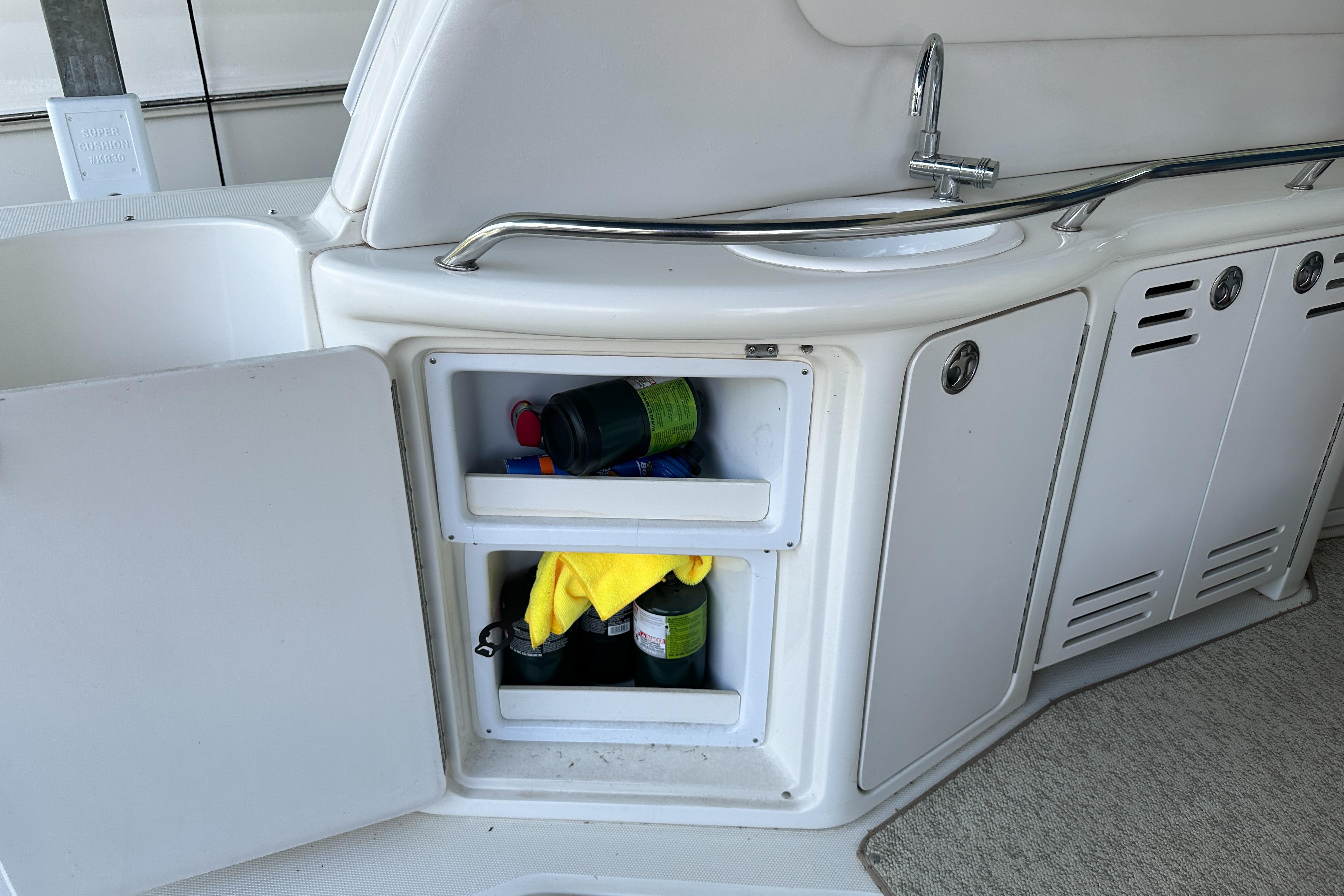 2001 Sea Ray 410 Sundancer boat kitchenette with open storage and sink.