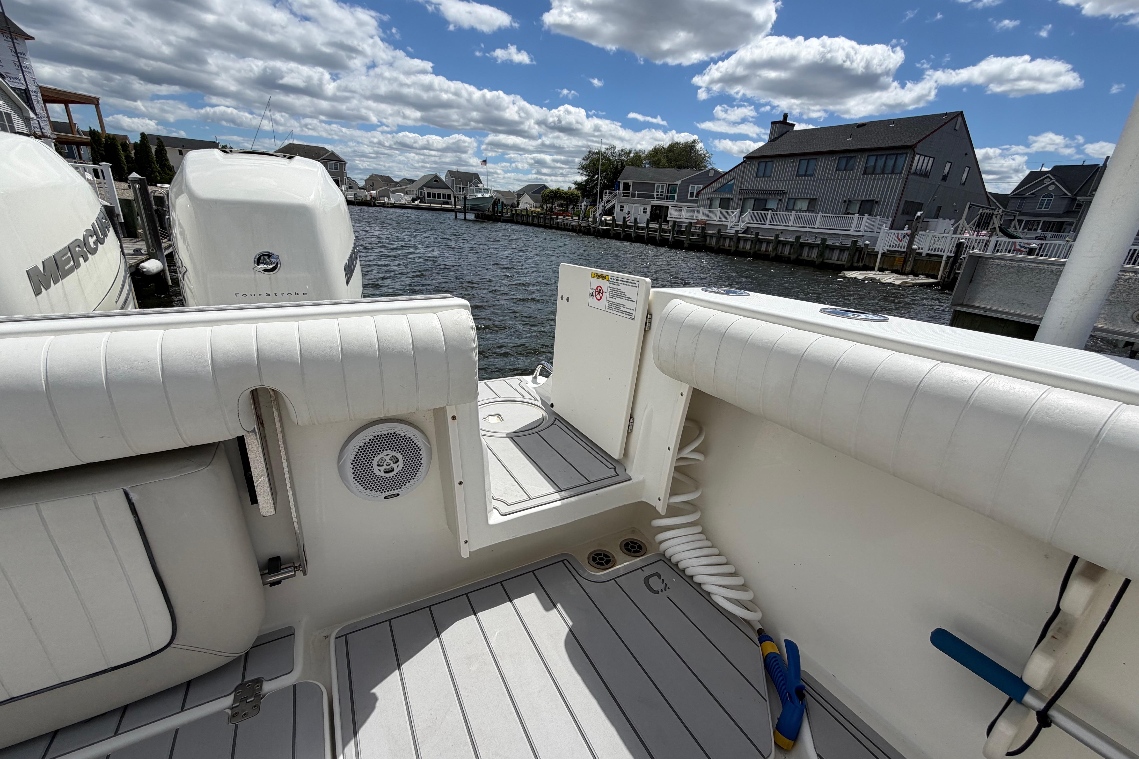 2017 Mako 284 Center Console boat docked by waterfront homes under a cloudy sky.