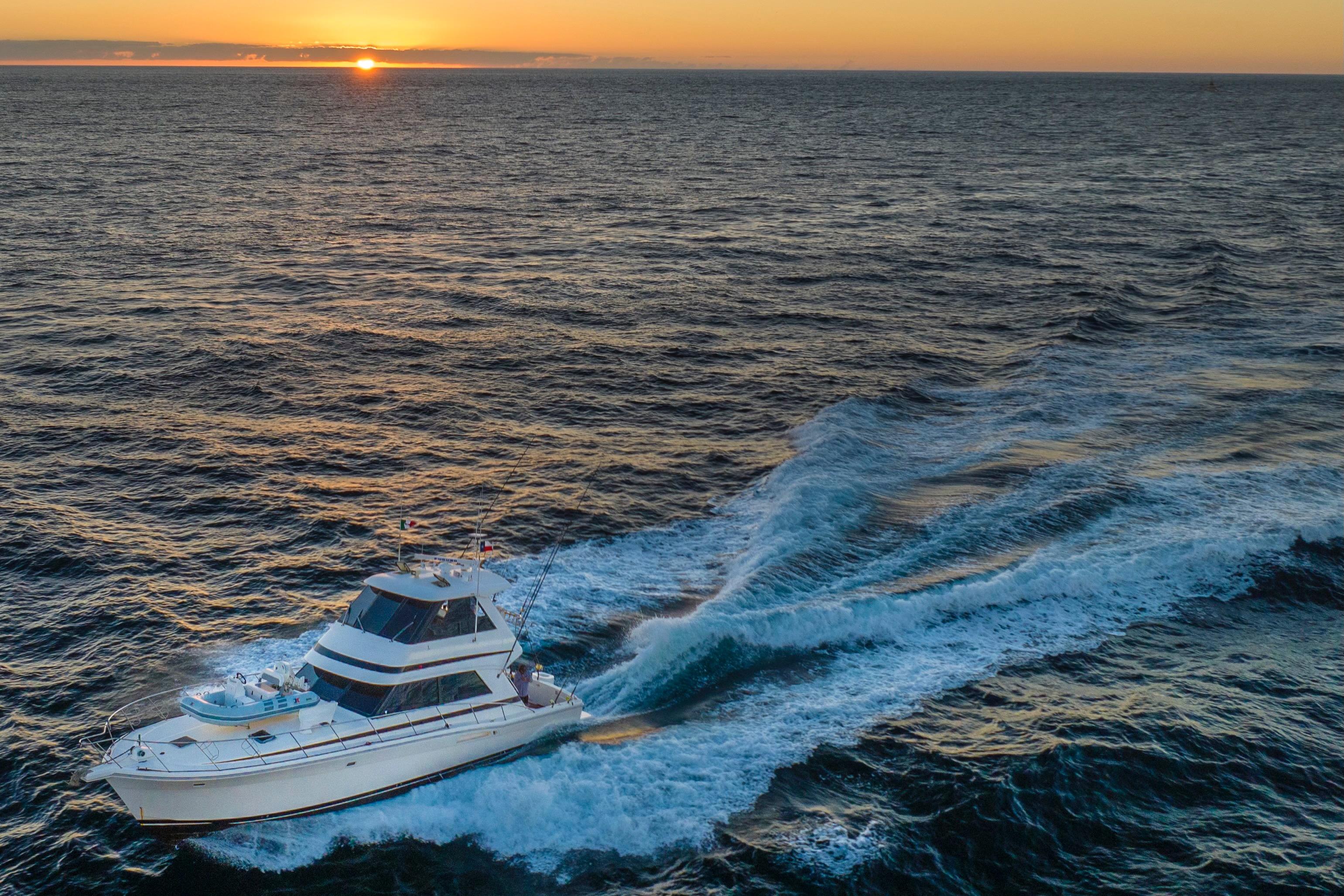 Riviera 48 Enclosed Flybridge yacht cruising at sunset, 2000 model, ocean view.