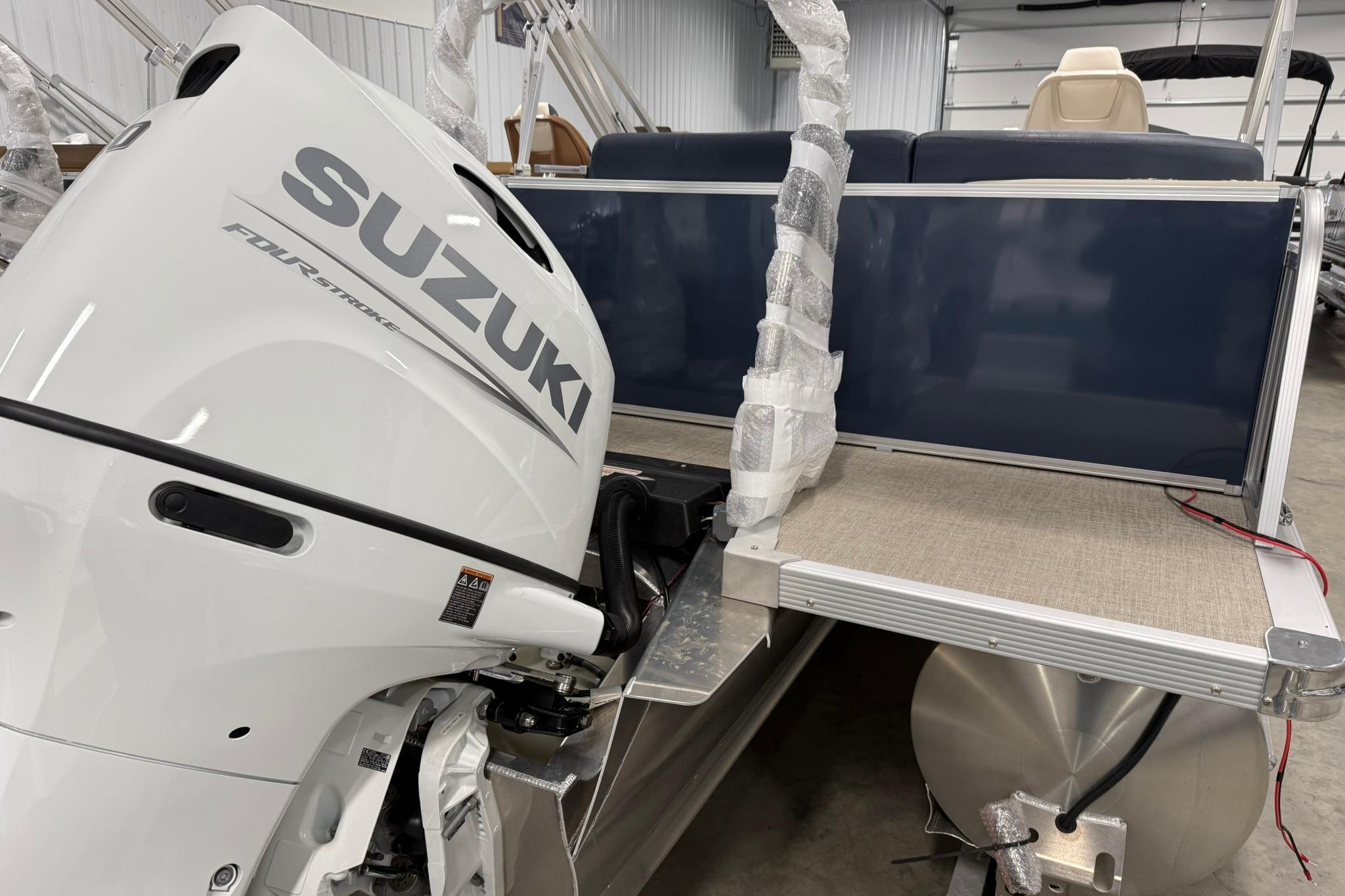 2026 Avalon LSZ Elite 21' with Suzuki outboard motor in a showroom.