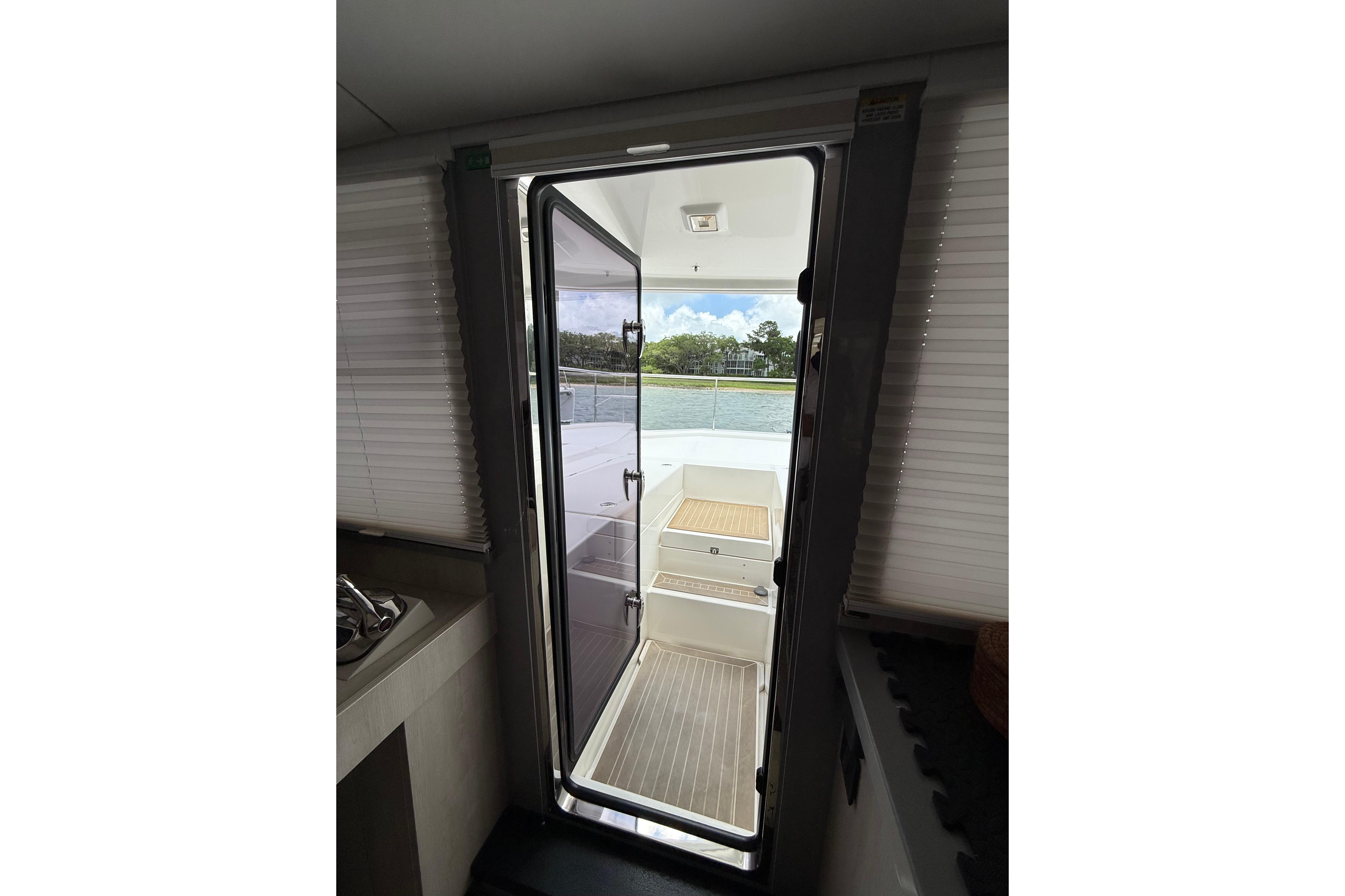 Interior view of 2021 Leopard 43 Powercat, showing open door to deck and scenic water view.
