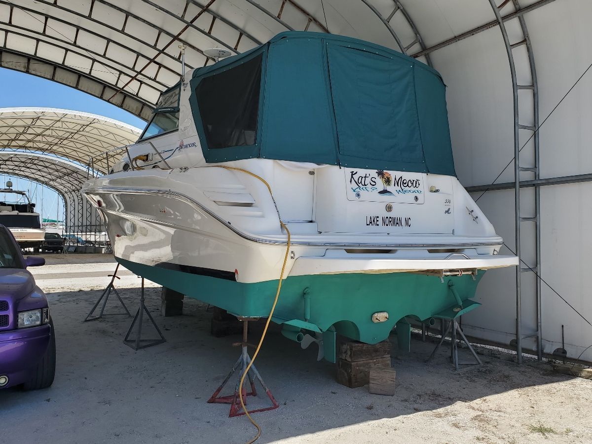 A 1995 Sea Ray Sundancer 330 is on blocks in a covered area.