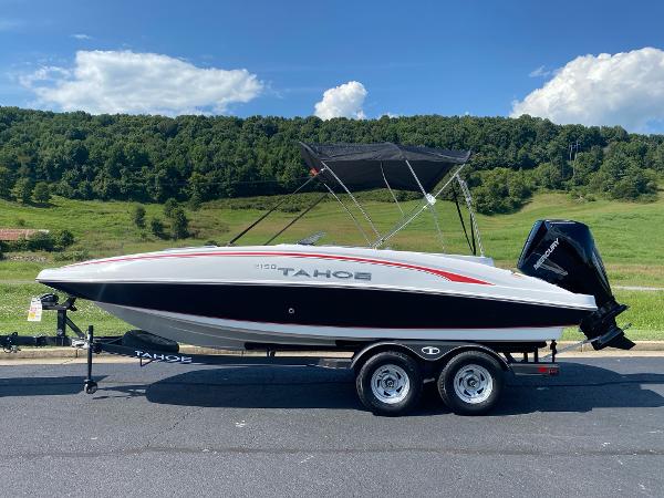 2024 Tahoe 2150 boat on trailer, parked outdoors with scenic green hills in background.