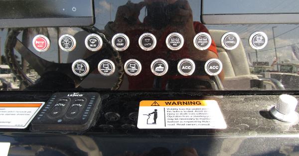 Control panel of a 2024 Wellcraft 263 Fisherman boat with various buttons and warning labels.