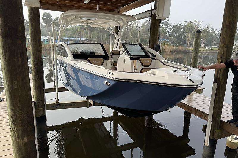 2023 Yamaha 275SDX boat suspended on a lift over water at a dock.