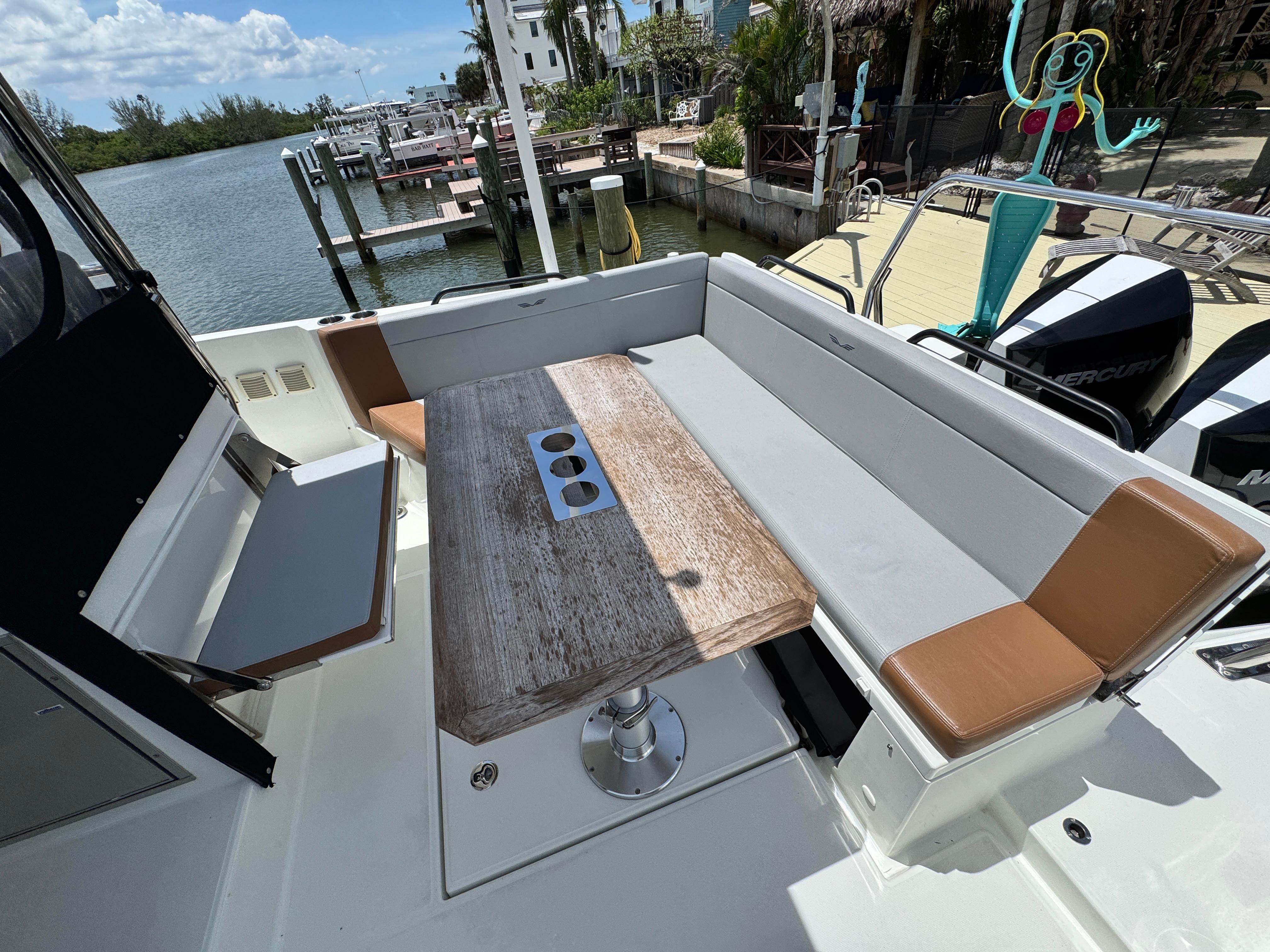 2022 Beneteau Flyer 9 SUNdeck boat with spacious seating and wooden table, docked by the water.