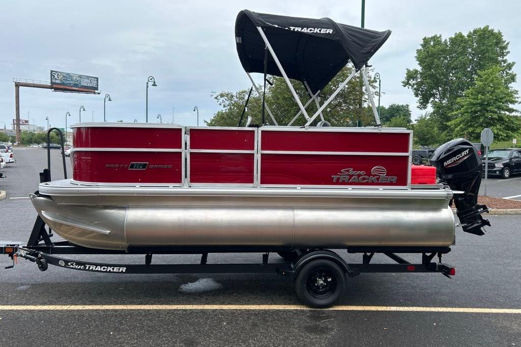2026 Sun Tracker Party Barge 16 DLX pontoon boat on trailer in parking lot.