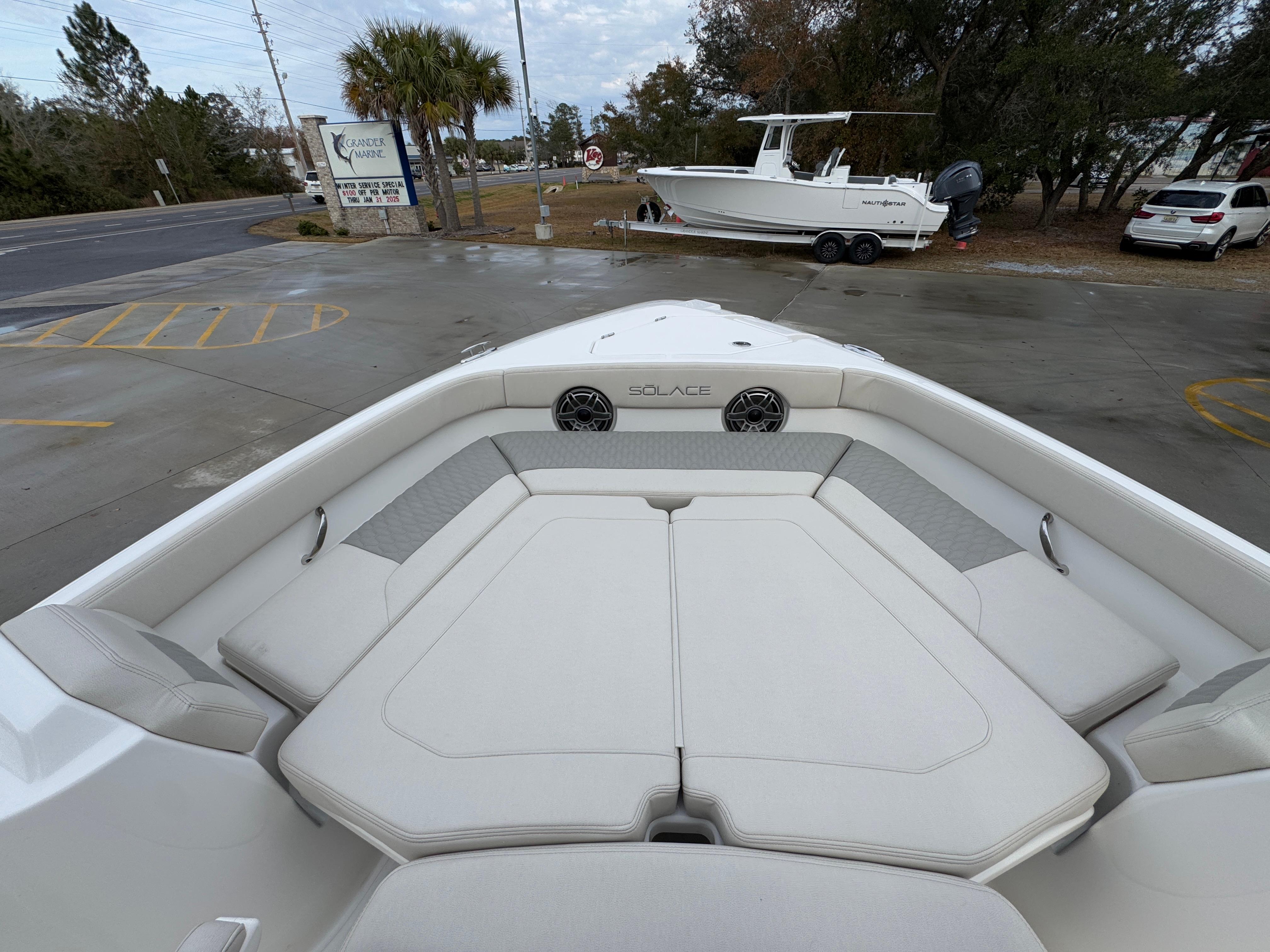 2025 Solace 28 HCS boat interior with cushioned seating and speakers, parked outdoors.