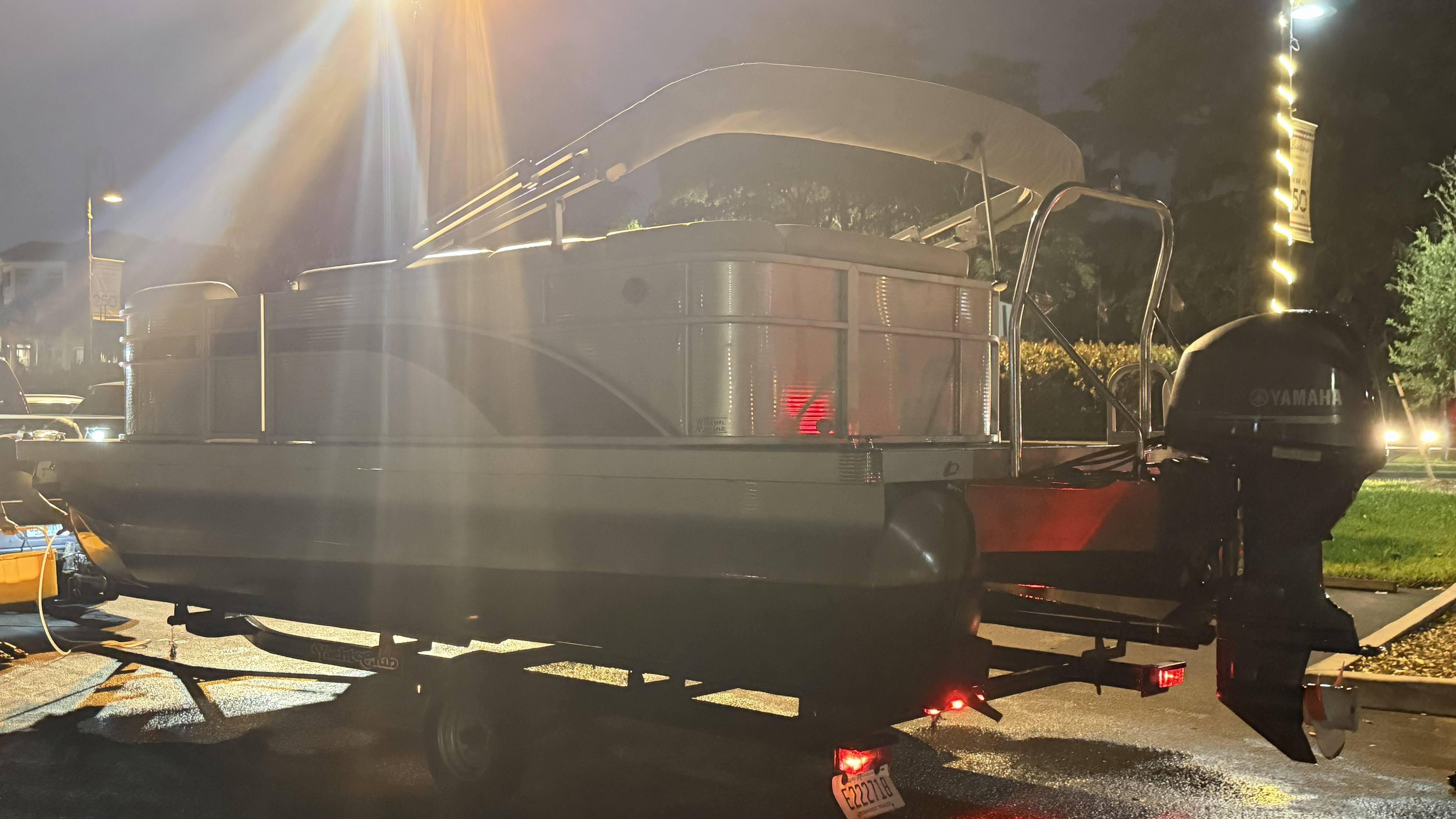 A Bennington pontoon boat on a trailer at night, illuminated by streetlights.