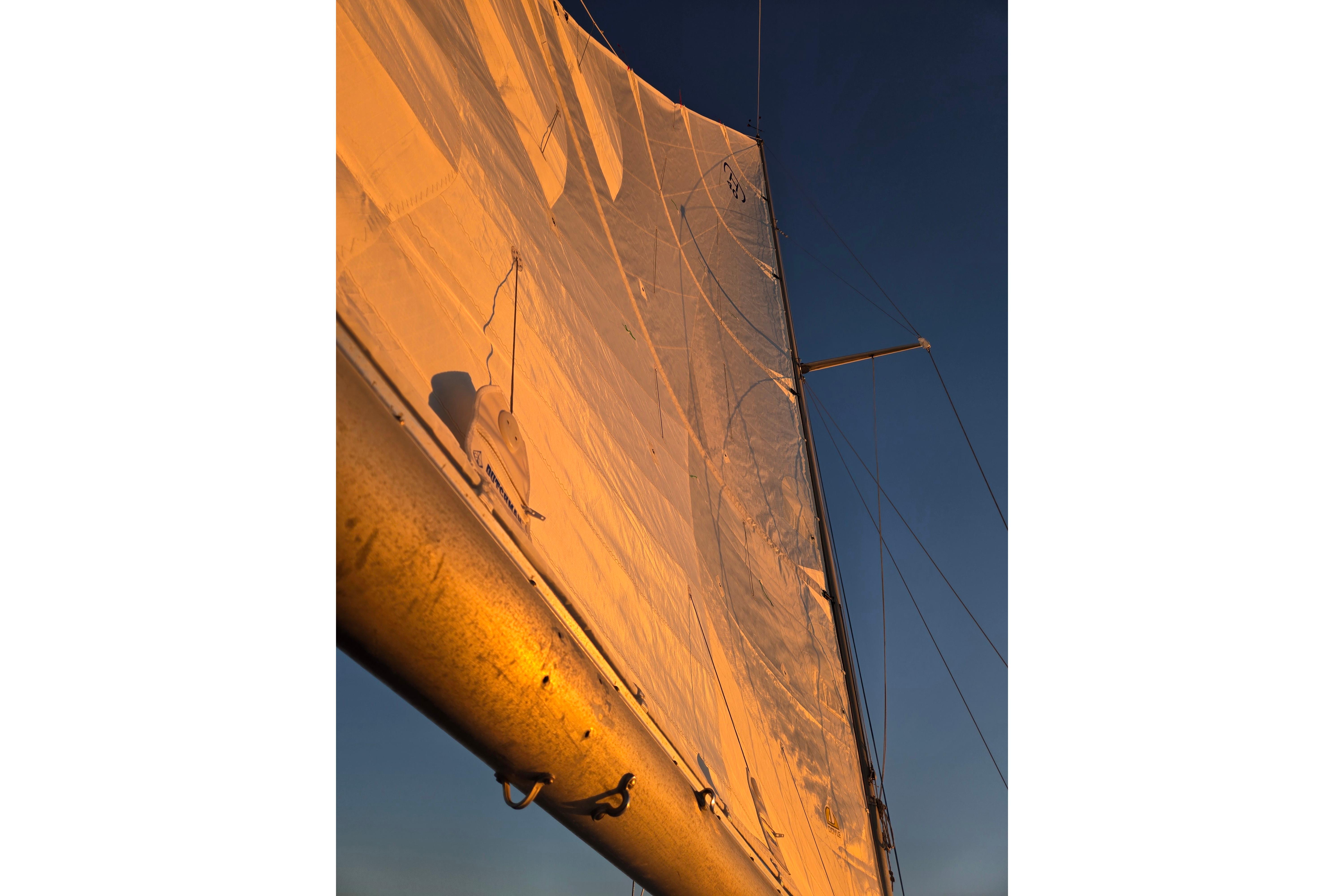 Sail of a 1970 Hinckley Bermuda 40 yacht illuminated by sunset light.
