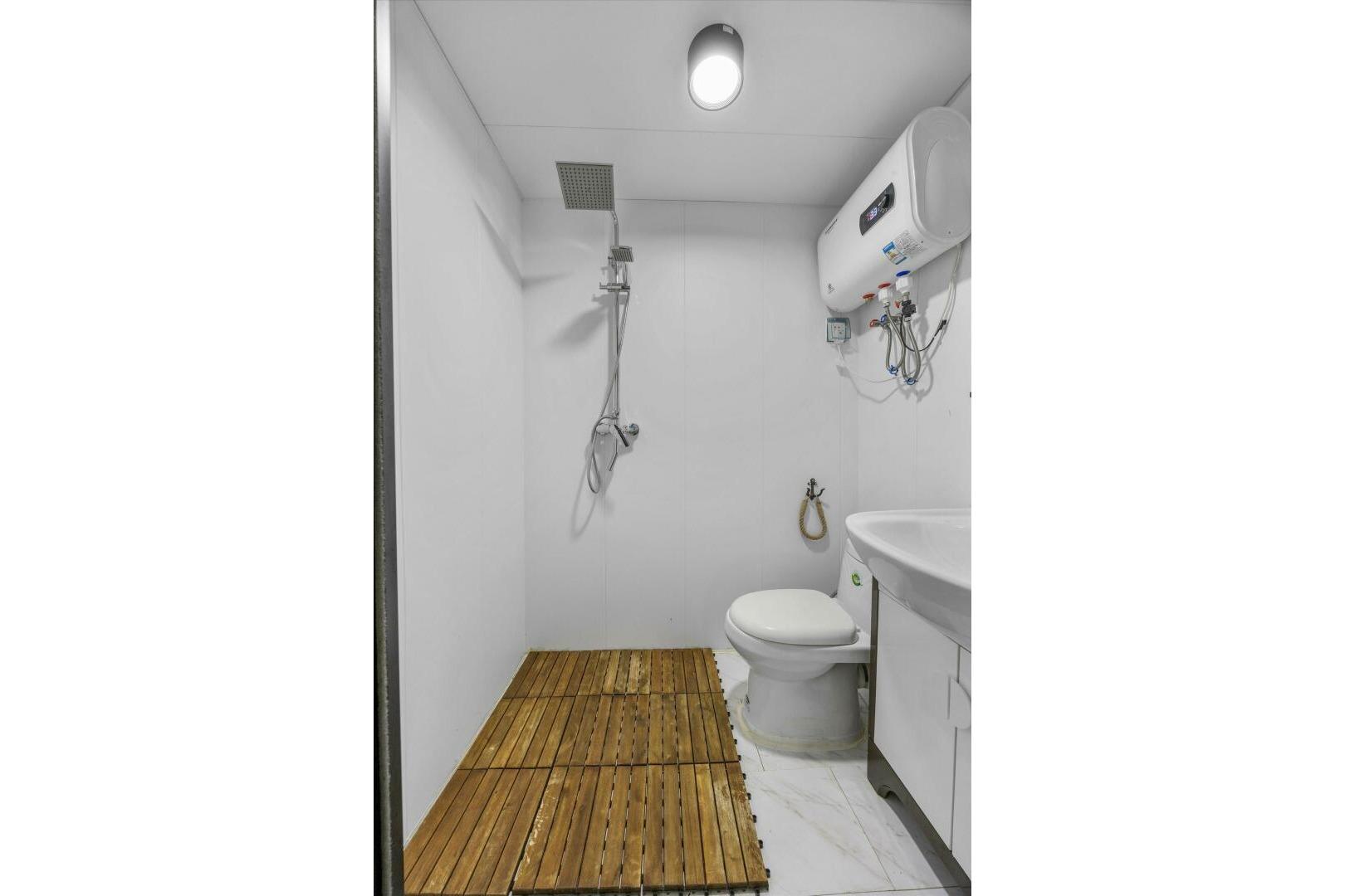 Modern bathroom with shower, toilet, wooden floor, and water heater, Gospel 39, 2024 model.