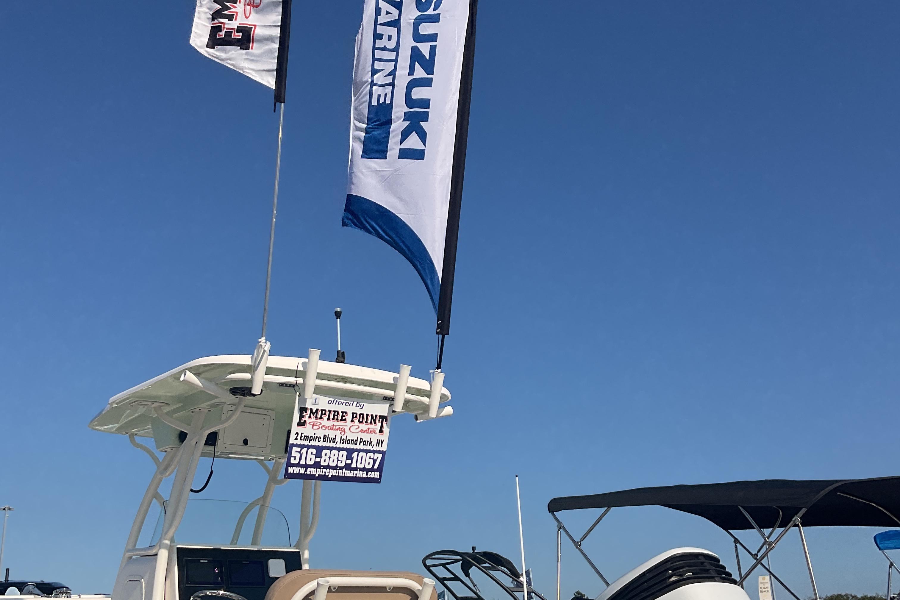 2023 Sea Born SX239 Offshore boat with Suzuki Marine flags under clear blue sky.