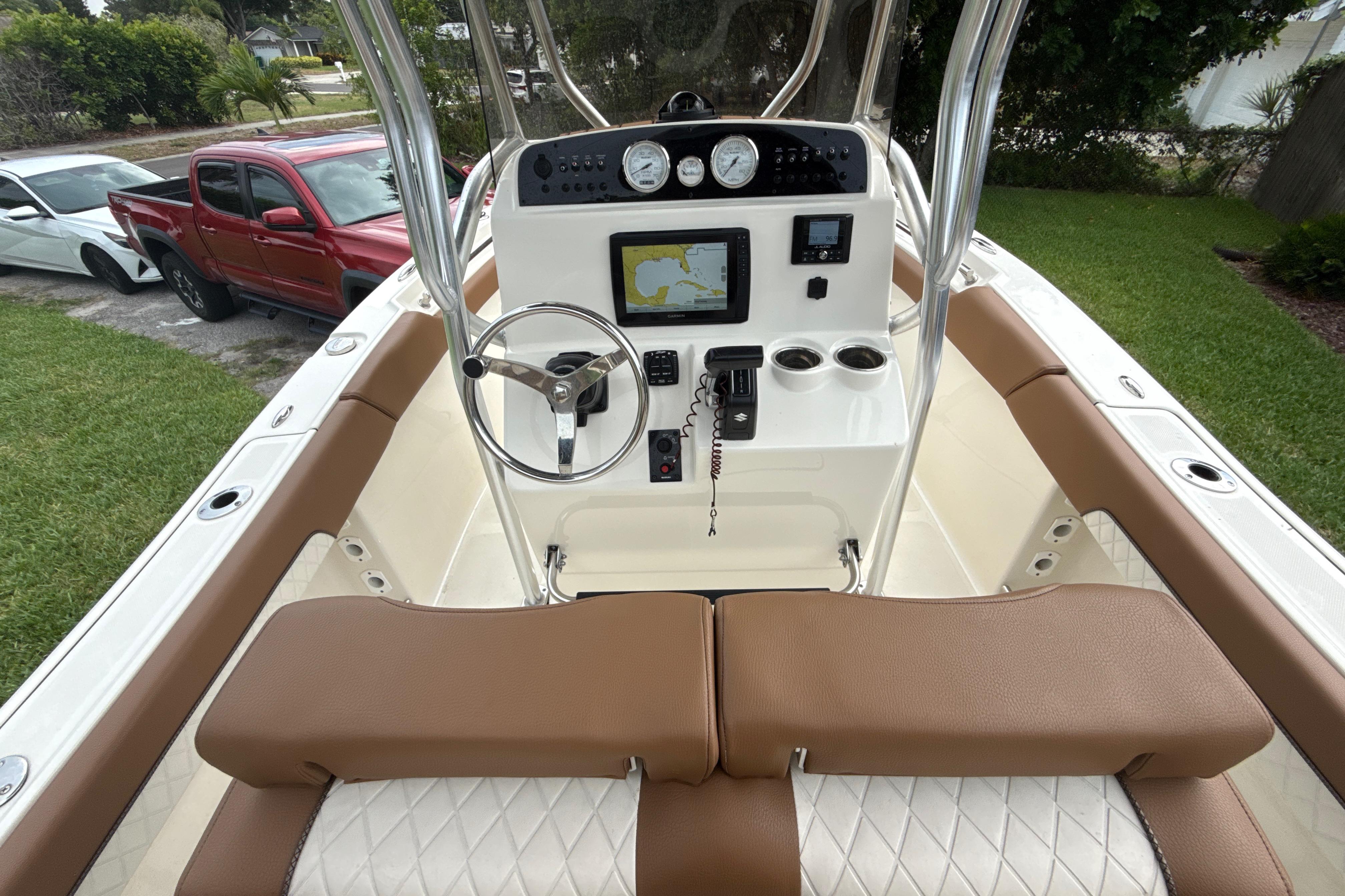 2023 Pioneer 202 Islander boat cockpit with steering wheel, navigation system, and brown seating.