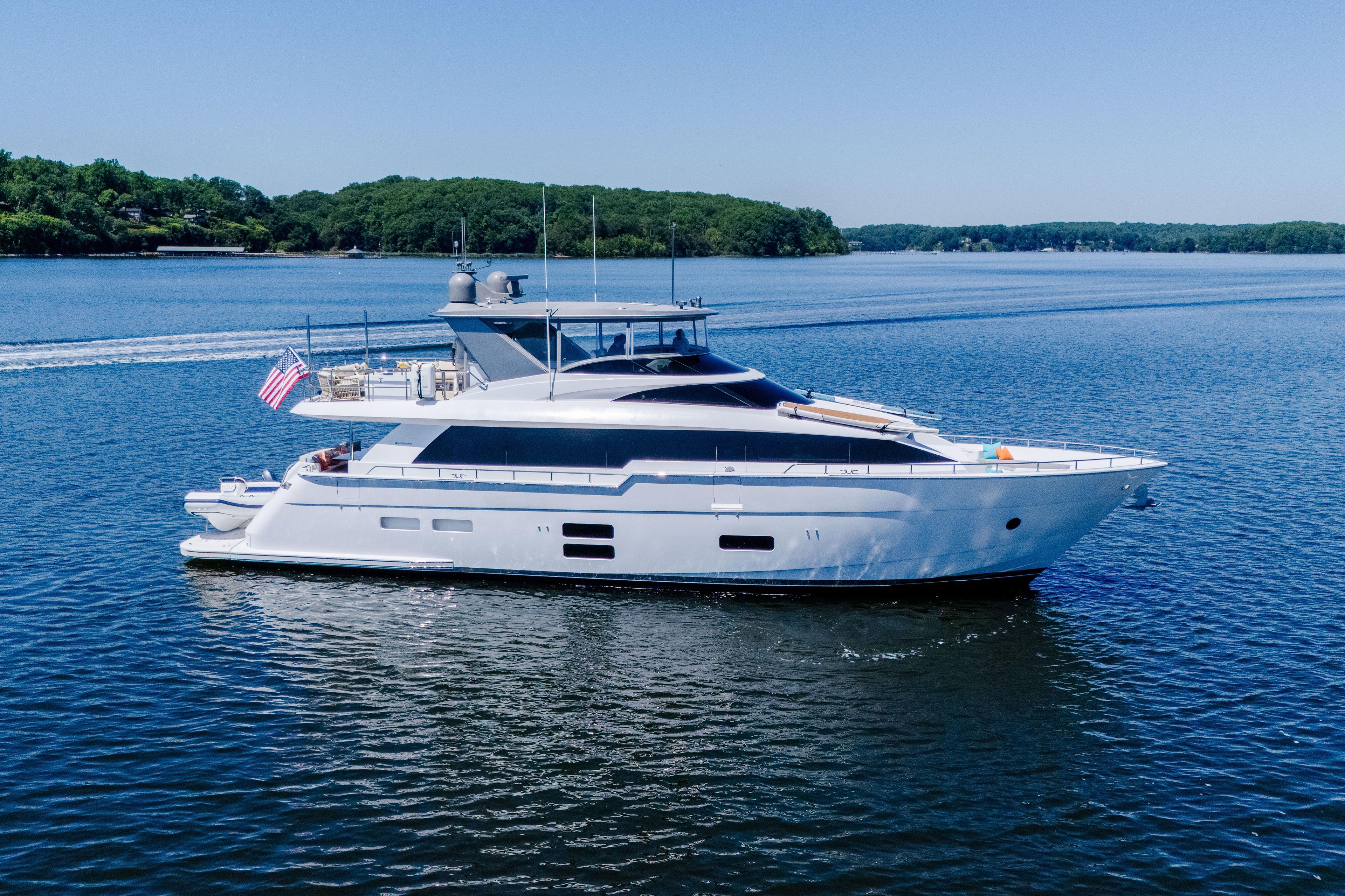 2021 Hatteras M75 Panacera yacht cruising on a serene lake under clear skies.