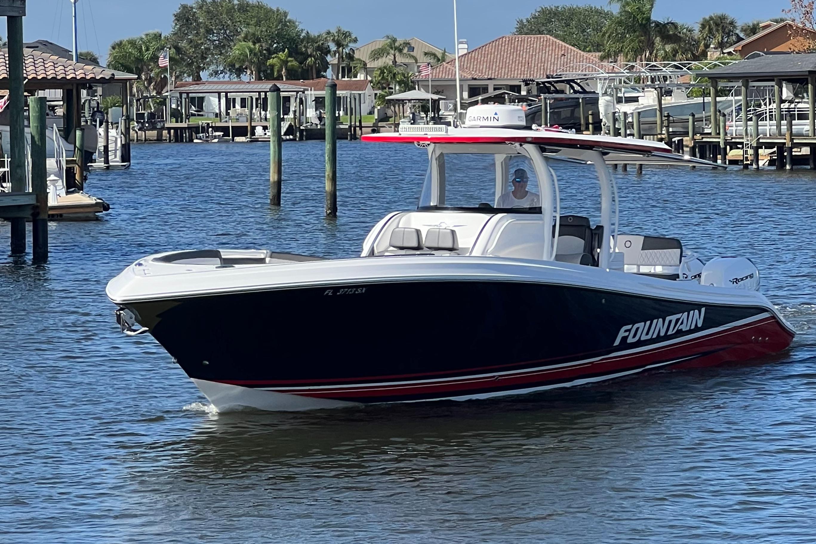2021 Fountain 39 NX boat cruising in a calm marina with waterfront homes.