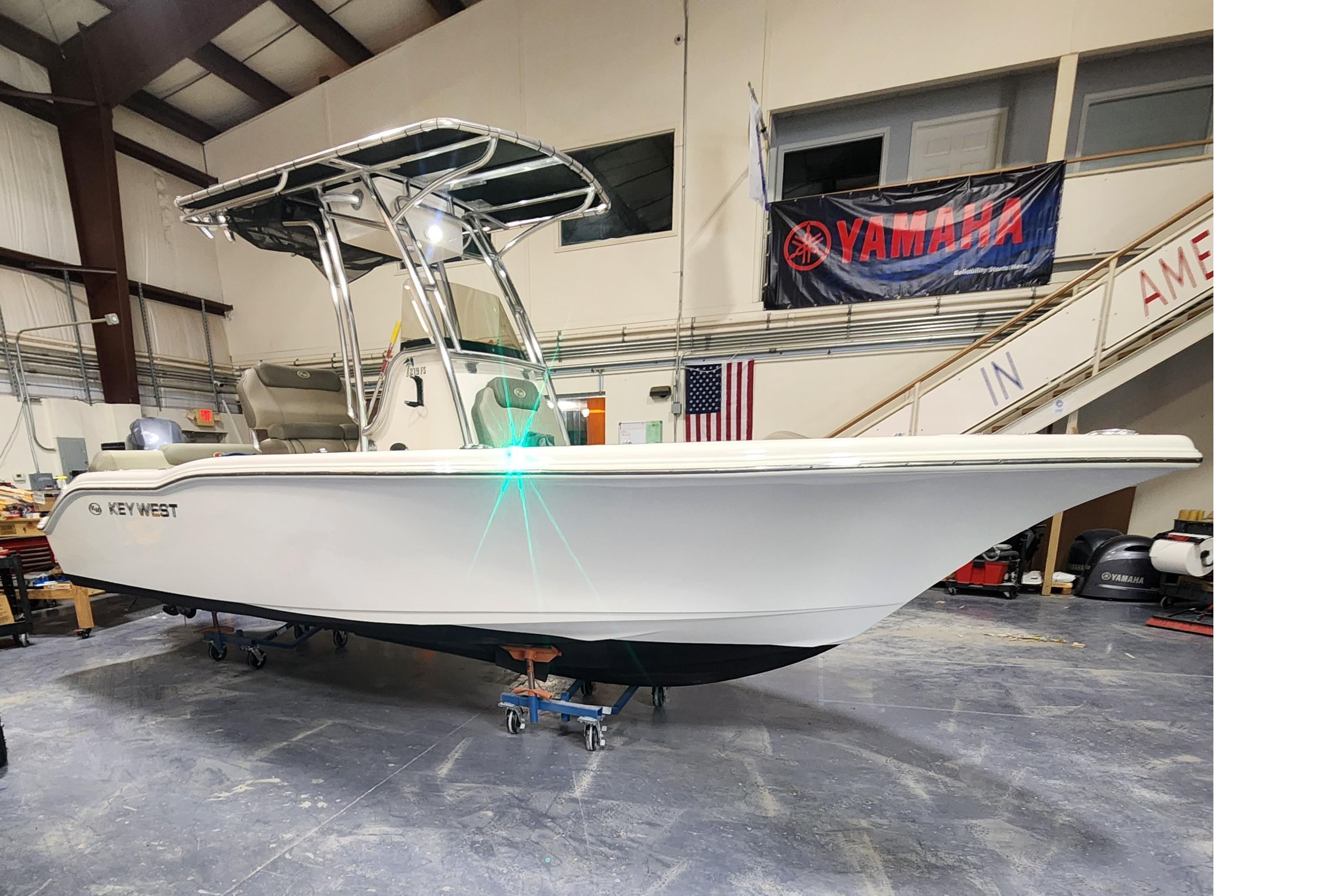 2023 Key West 219 FS boat in showroom with Yamaha banner and American flag.