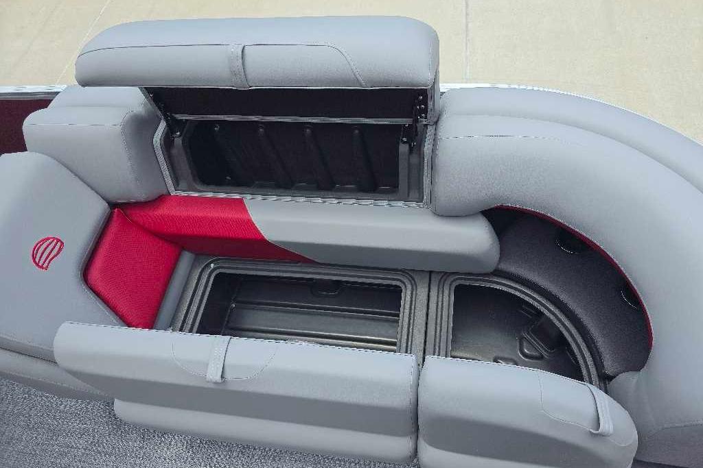 2026 Sun Tracker Party Barge 20 DLX seating with storage compartments, featuring gray and red upholstery.