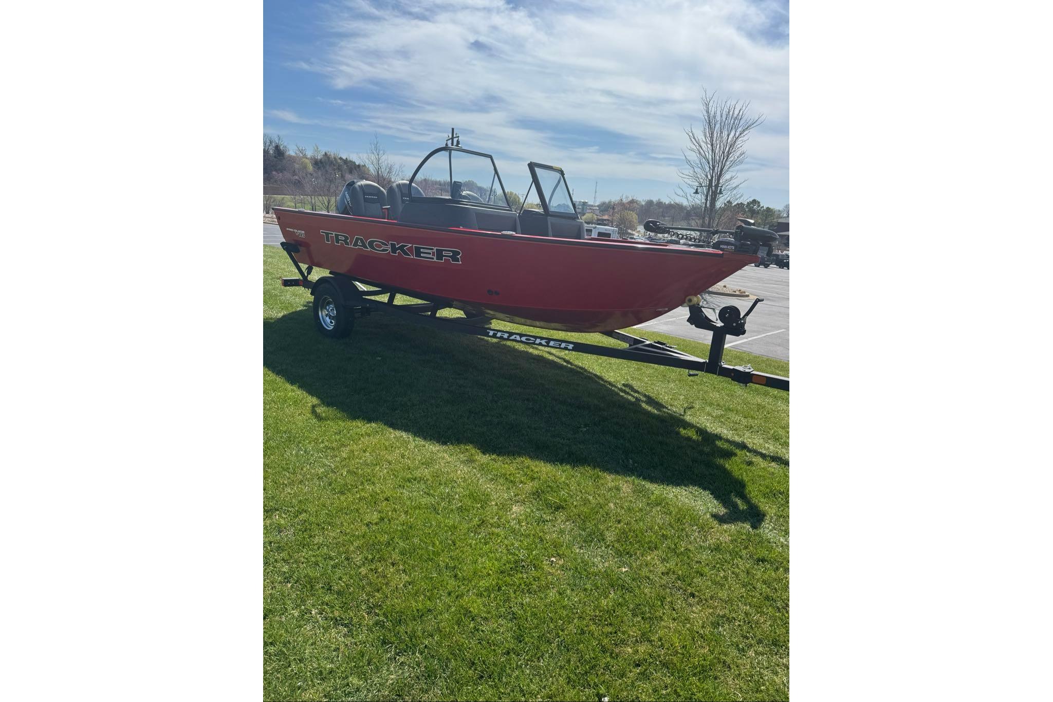 2026 Tracker Pro Guide V-16 WT boat on trailer, parked on grass under blue sky.