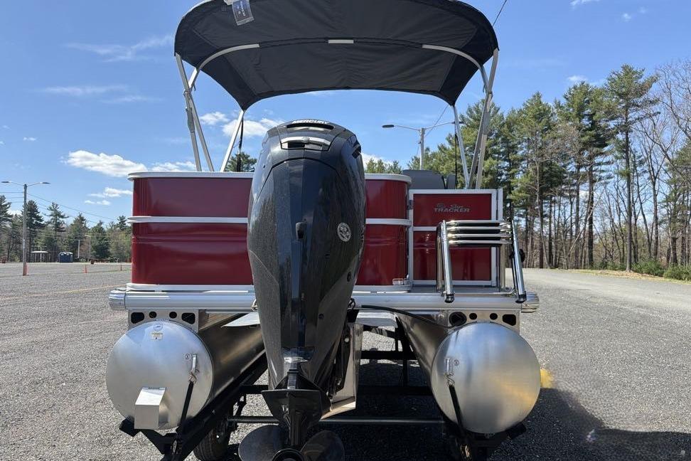 2026 Sun Tracker Party Barge 18 DLX pontoon boat with outboard motor, parked outdoors.