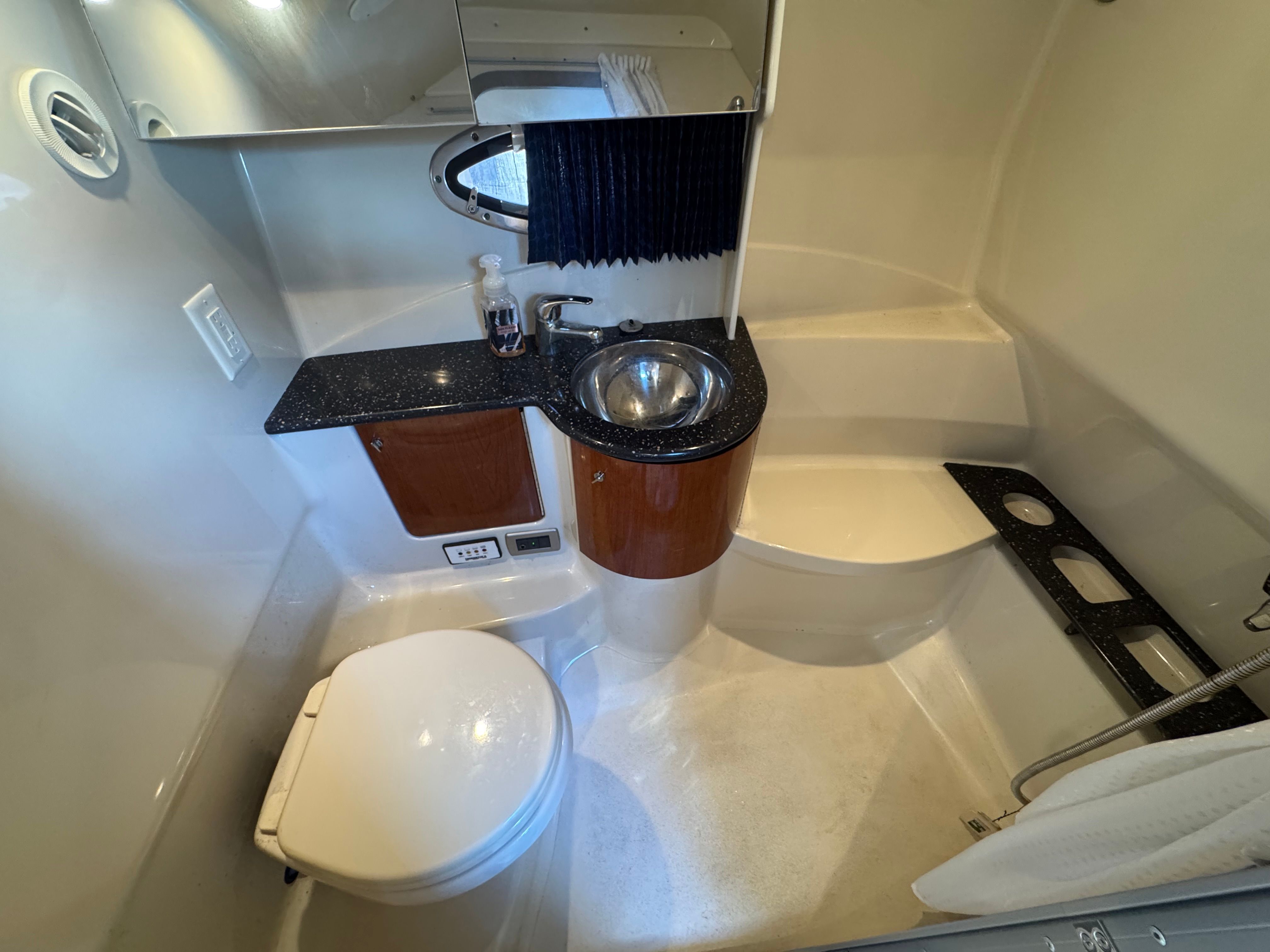 Compact bathroom with toilet, sink, and mirror inside a boat.