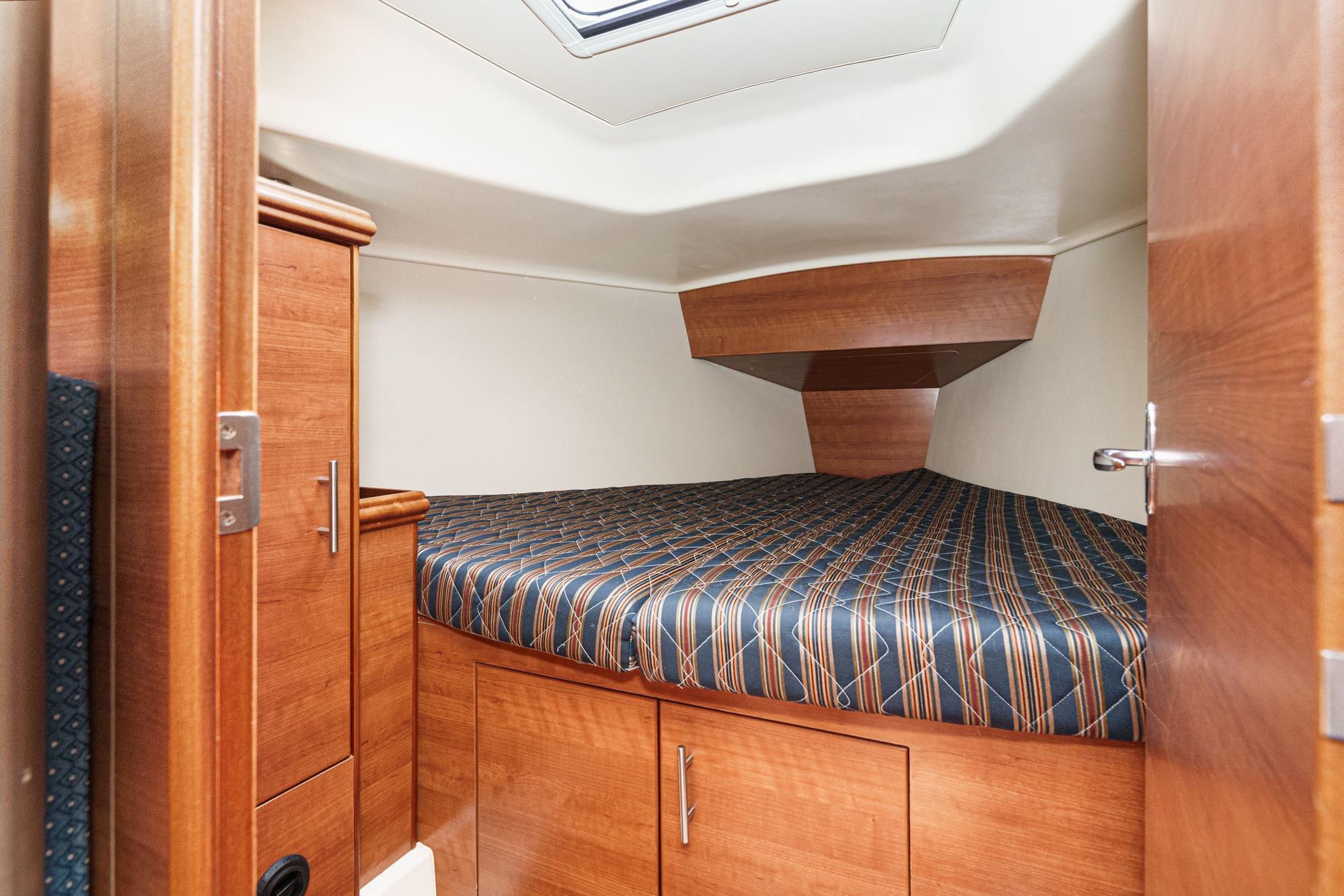 2015 Hunter 33 yacht cabin with wood finish and striped bedding.