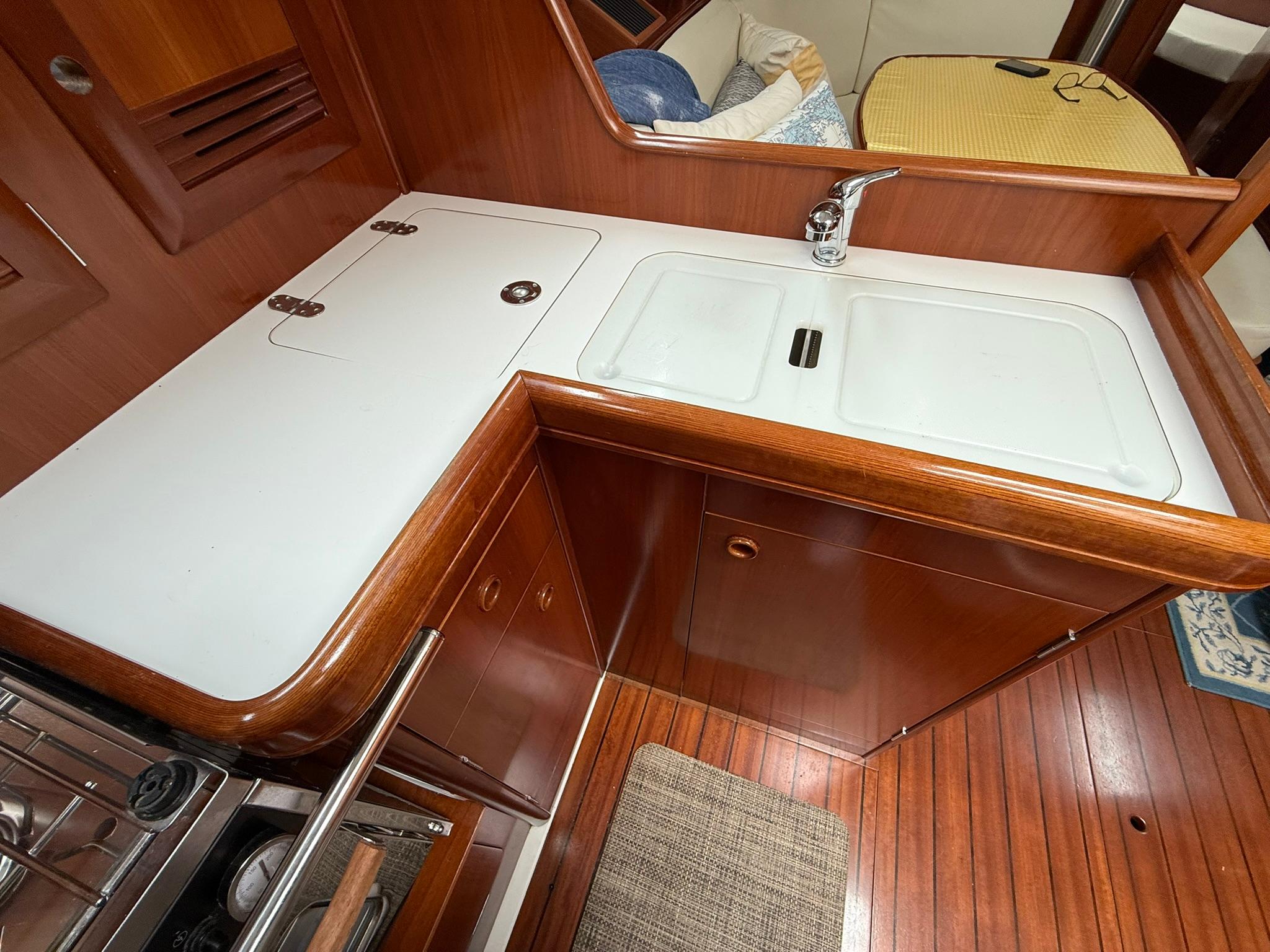 2003 Beneteau 393 yacht kitchen with wooden cabinetry and dual sink.