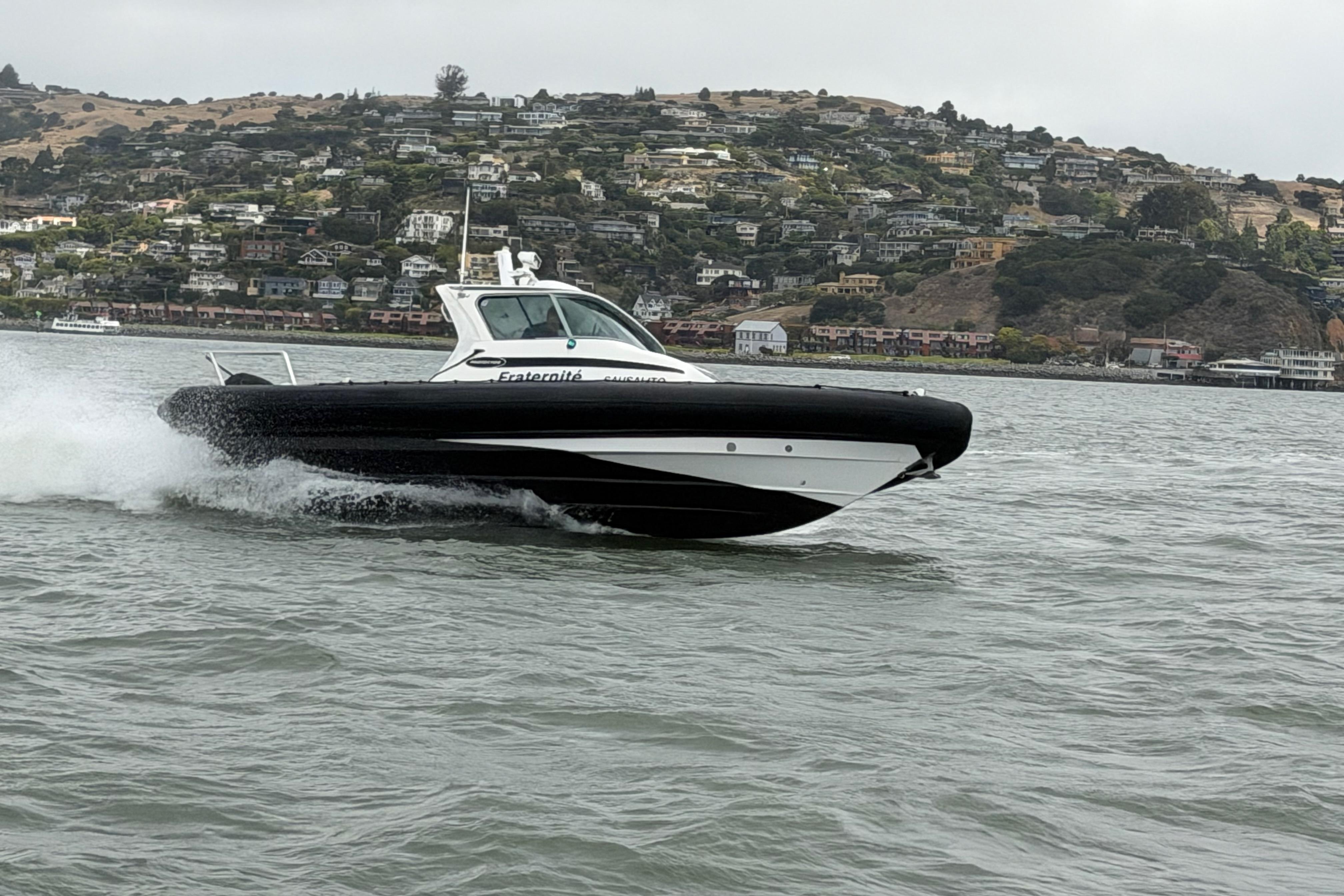 2016 Protector Targa 30 boat cruising on water with scenic hillside background.
