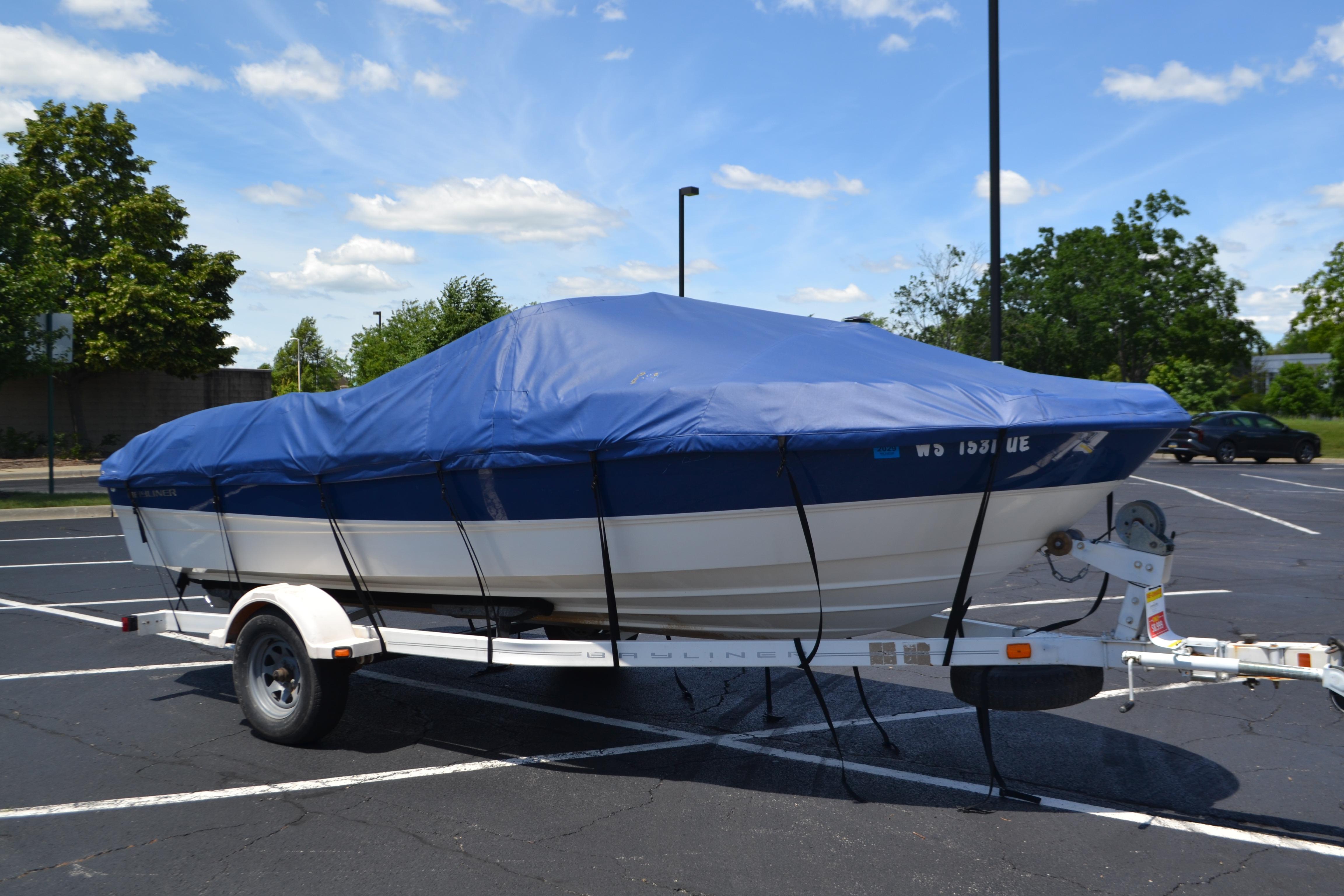 2009 Bayliner 185 Bowrider boat covered on trailer in parking lot.