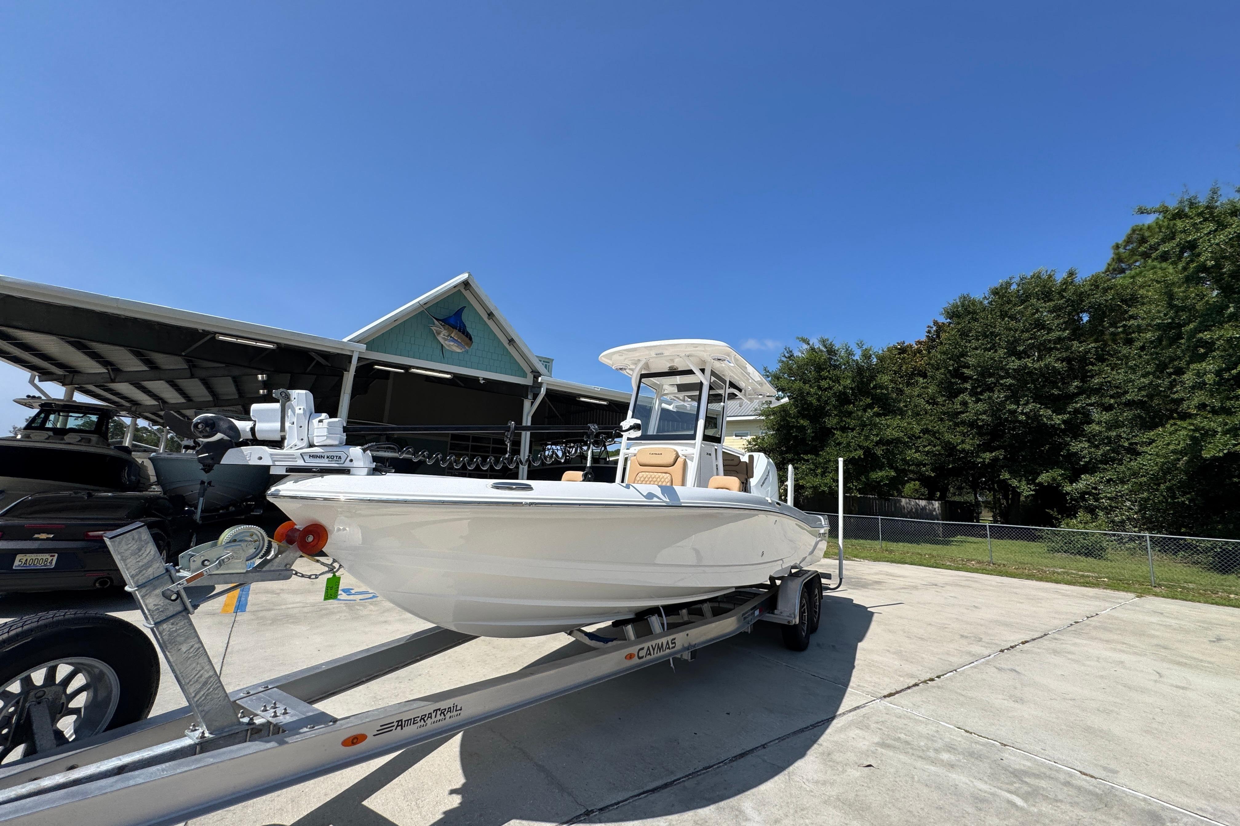 2027 Caymas 26 HB boat on trailer, parked outdoors under clear blue sky.