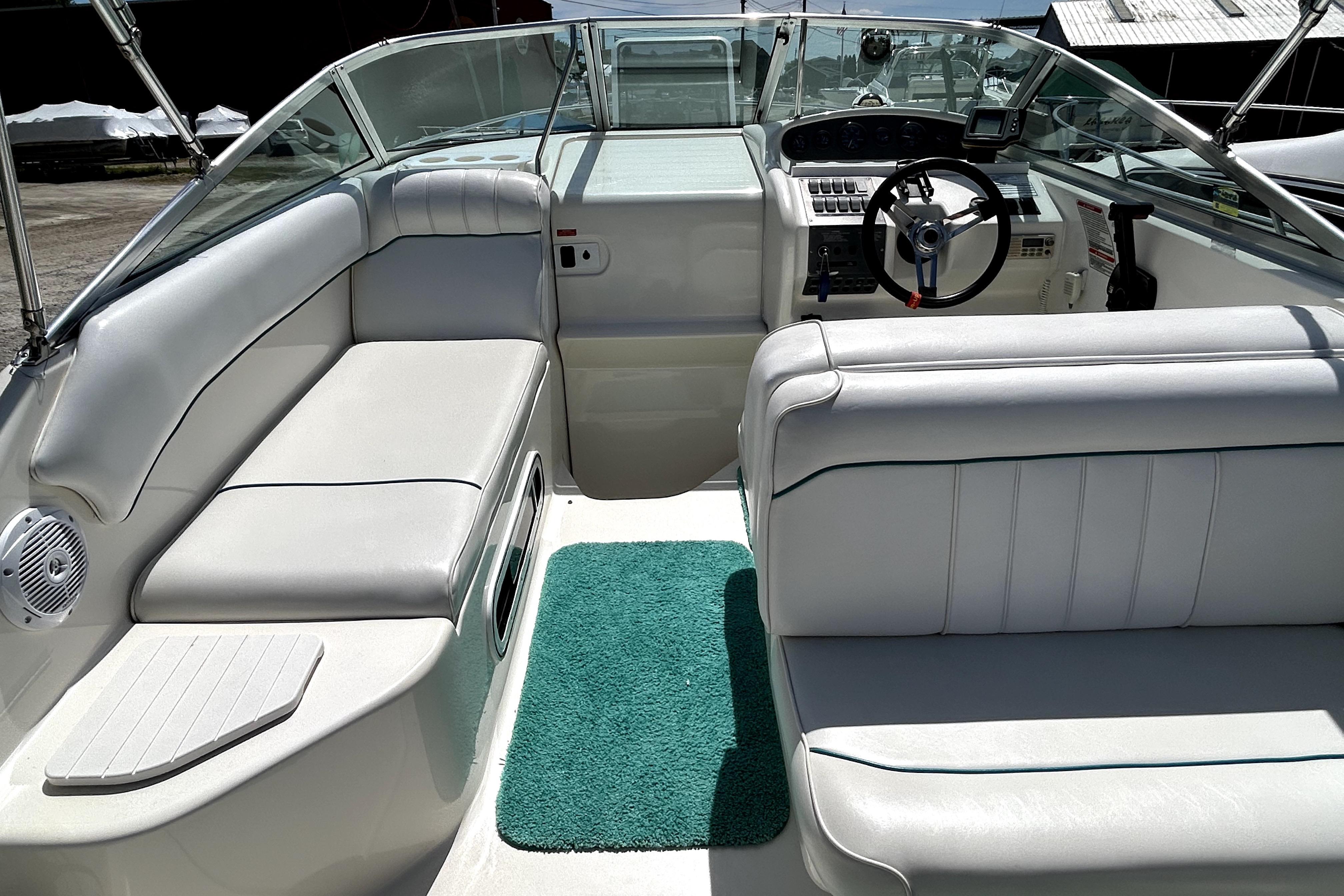 Interior of a 1995 Sea Ray 250 Sundancer boat with white seating and green carpet.