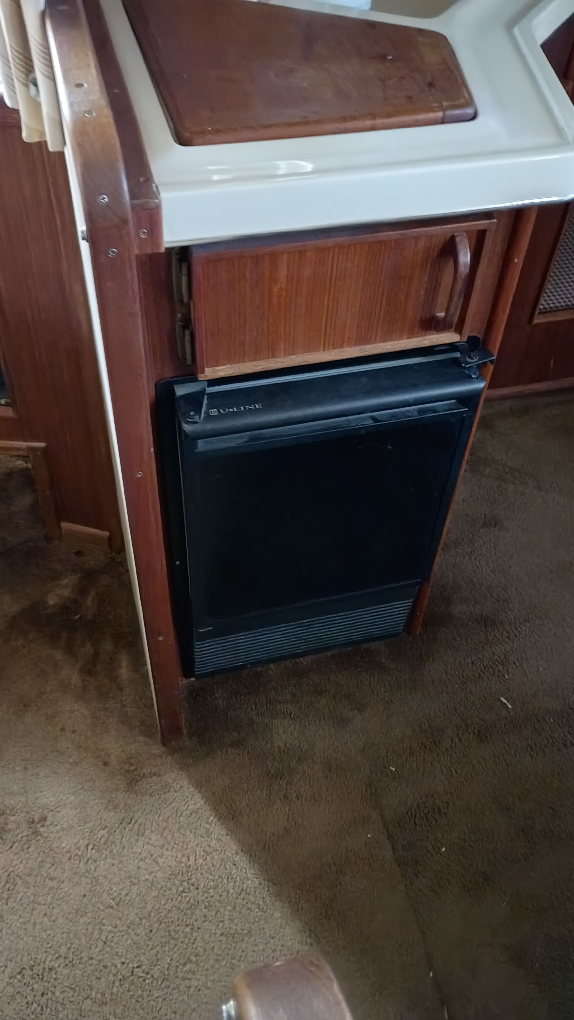 Interior of a 1986 Sea Ray Sundancer featuring a small refrigerator and wooden cabinetry.