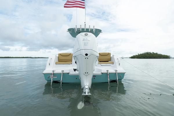 Manufacturer Provided Image: 2025 Sportsman Heritage 231 Center Console boat on calm water, rear view with American flag.