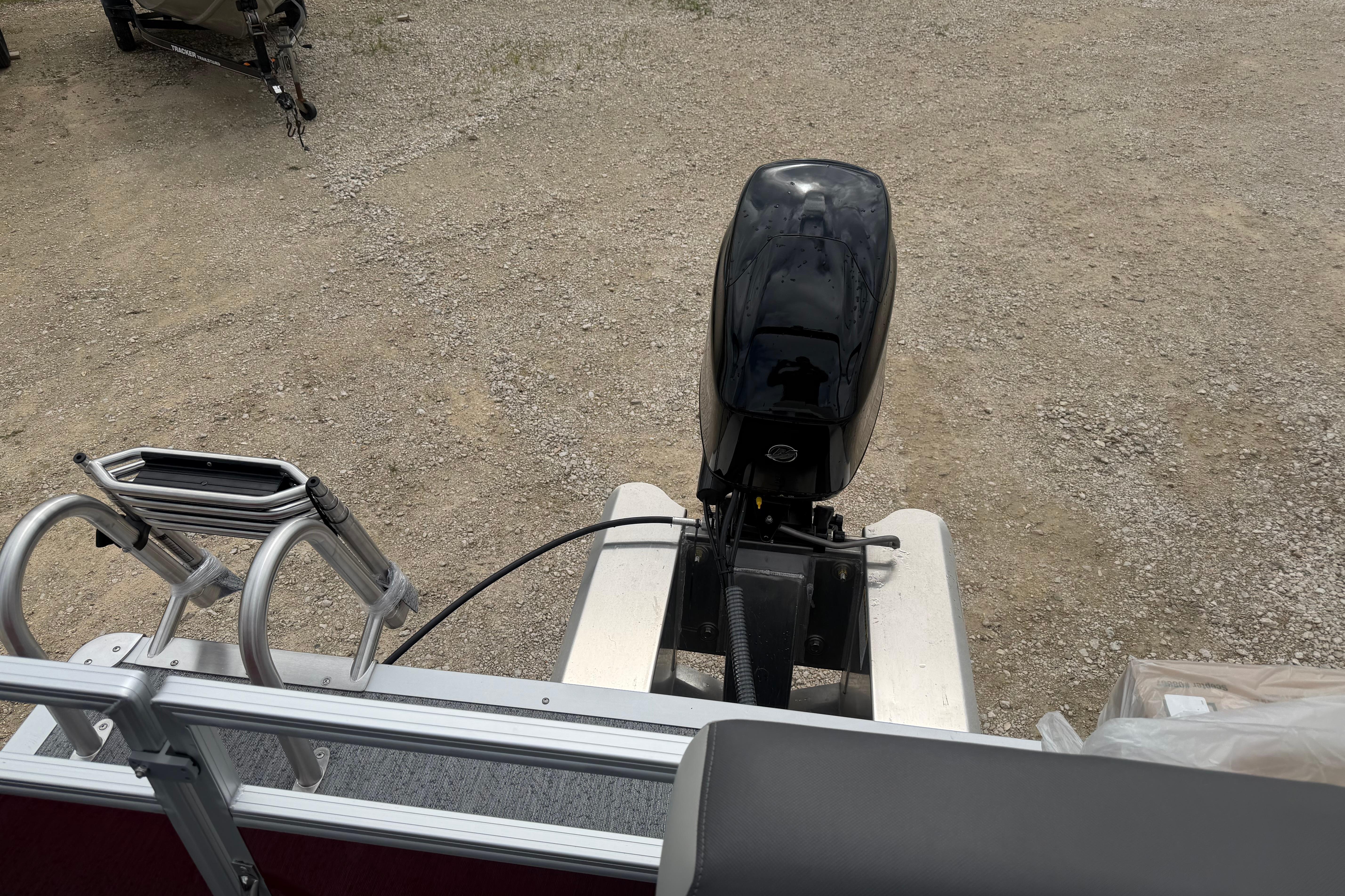 2026 Sun Tracker Bass Buggy 16 XL Select with outboard motor on gravel surface.