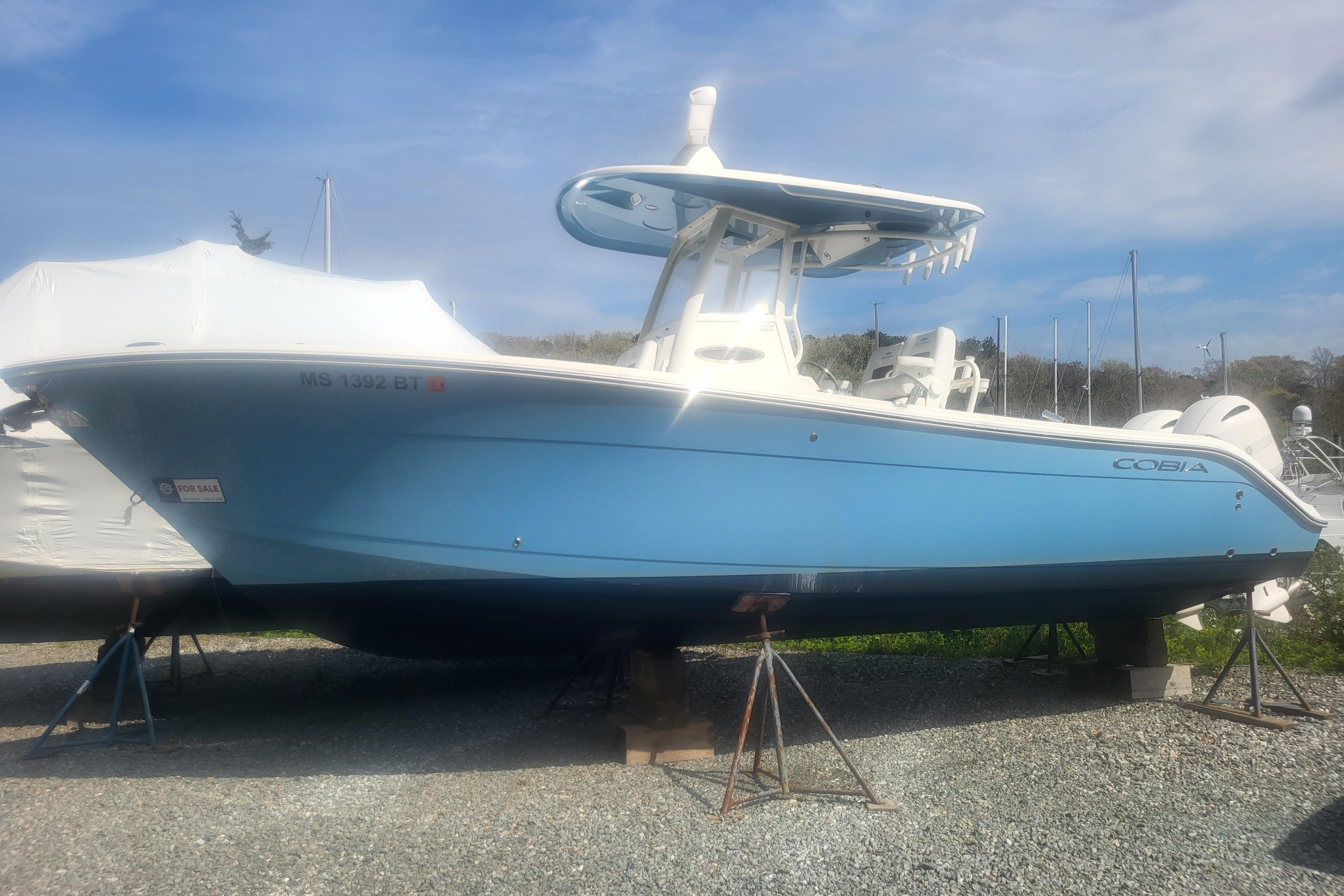 2022 Cobia 262 Center Console boat in blue, displayed on stands outdoors.