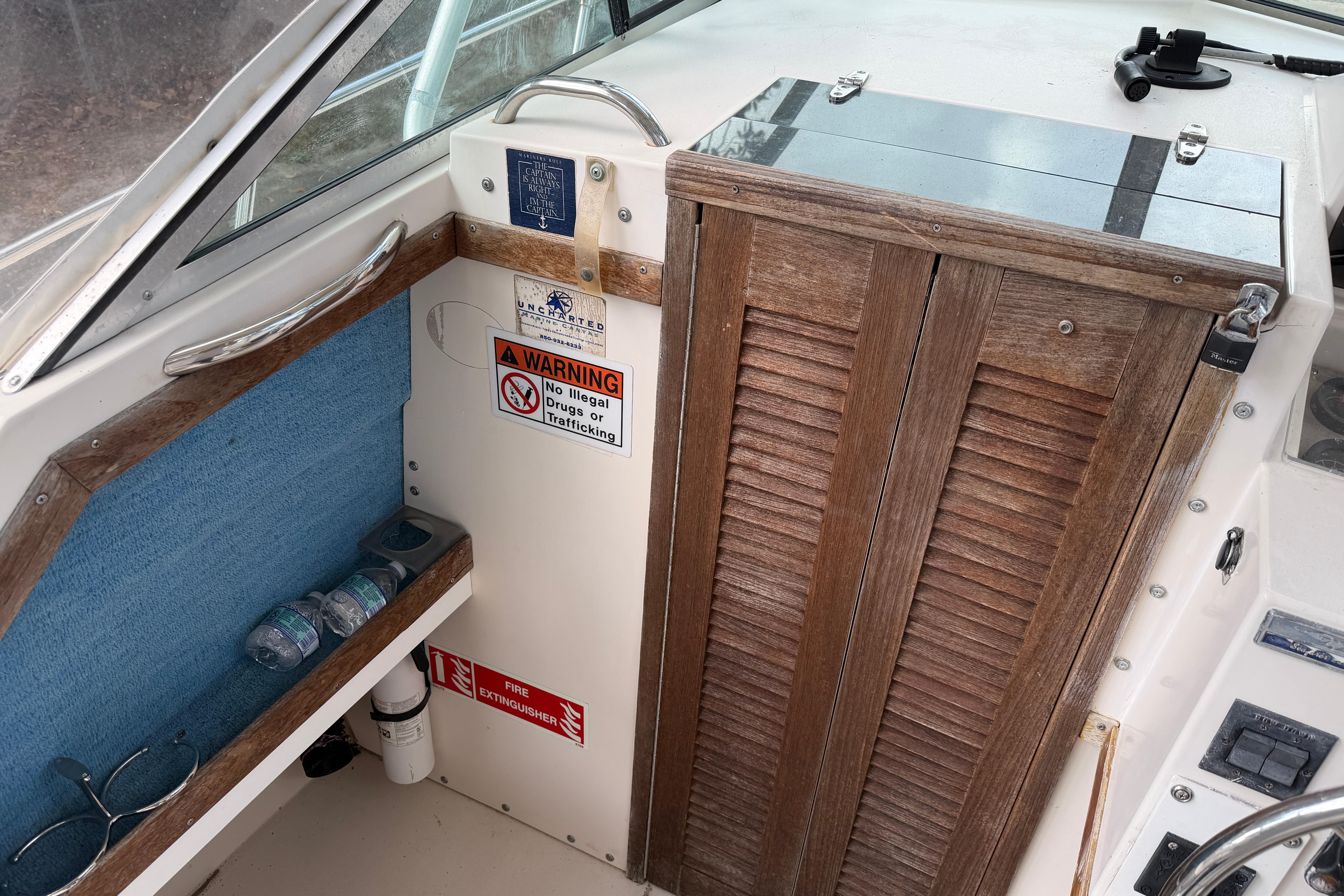 1987 Grady-White Seafarer 226 boat interior with wooden door, warning signs, and storage shelf.